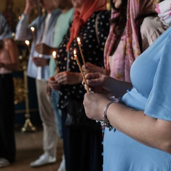 Репортажная съемка обряда Крещения: горящие свечи и молящиеся родственники в церкви