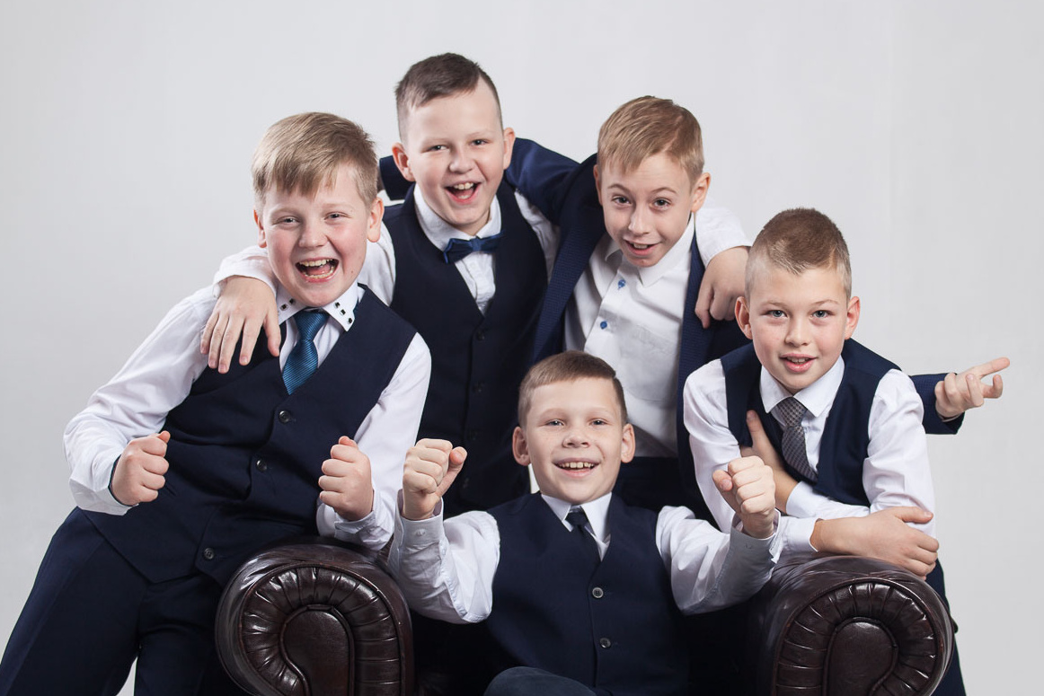 Пять мальчиков (выпускников 4 класса) в жилетках темно-синих фотографируются в фотостудии.