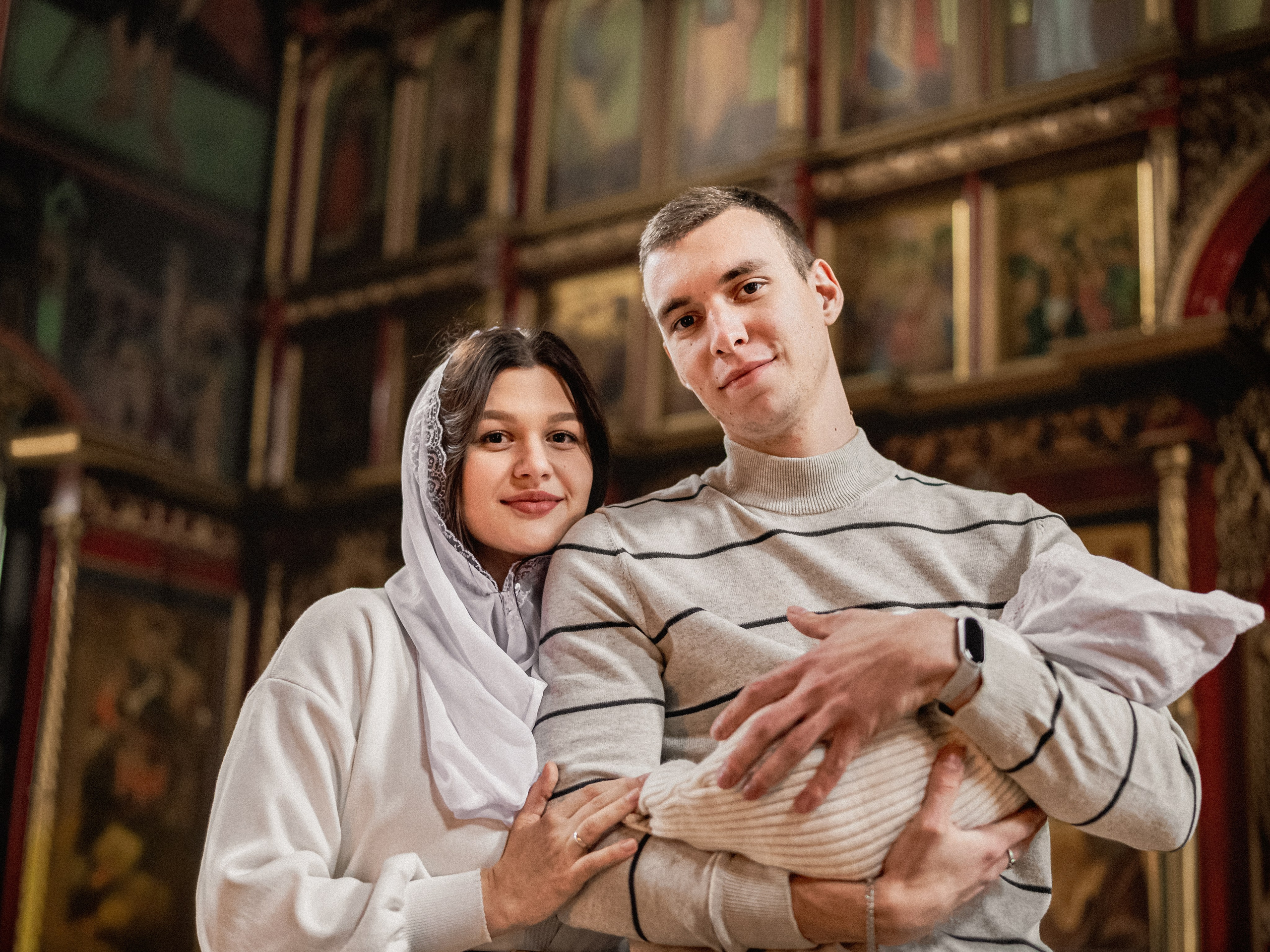 Счастливые родители после крещения малыша делают совместное фото