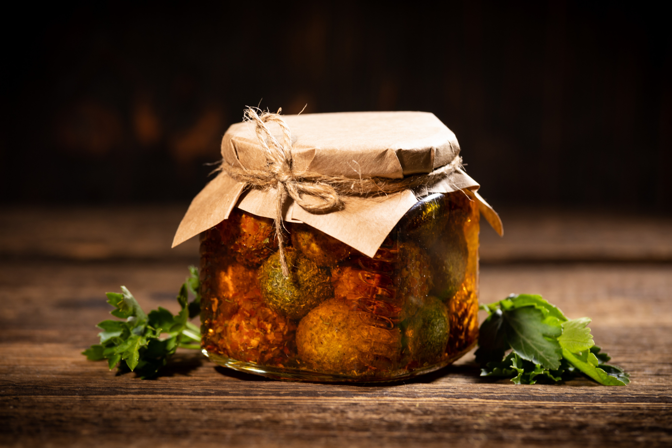 Стеклянная банка 390 мл с сырными шариками в масле крупным планом на фоне состаренных досок