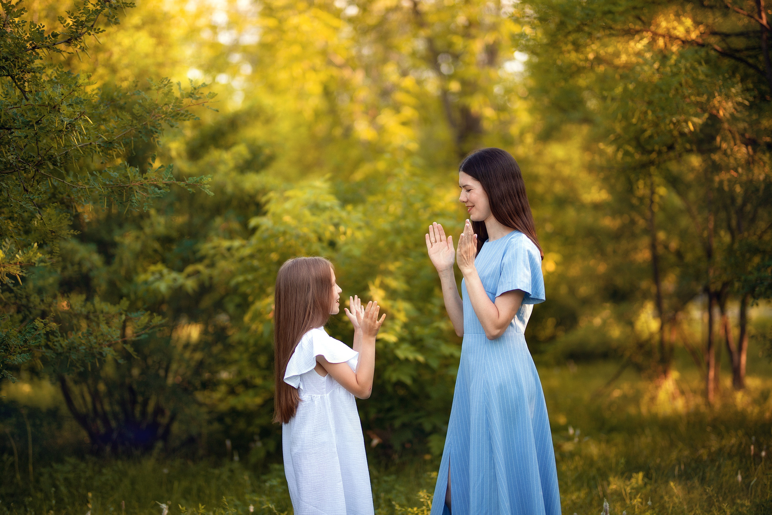 Мама и дочь играют в ладушки на природе