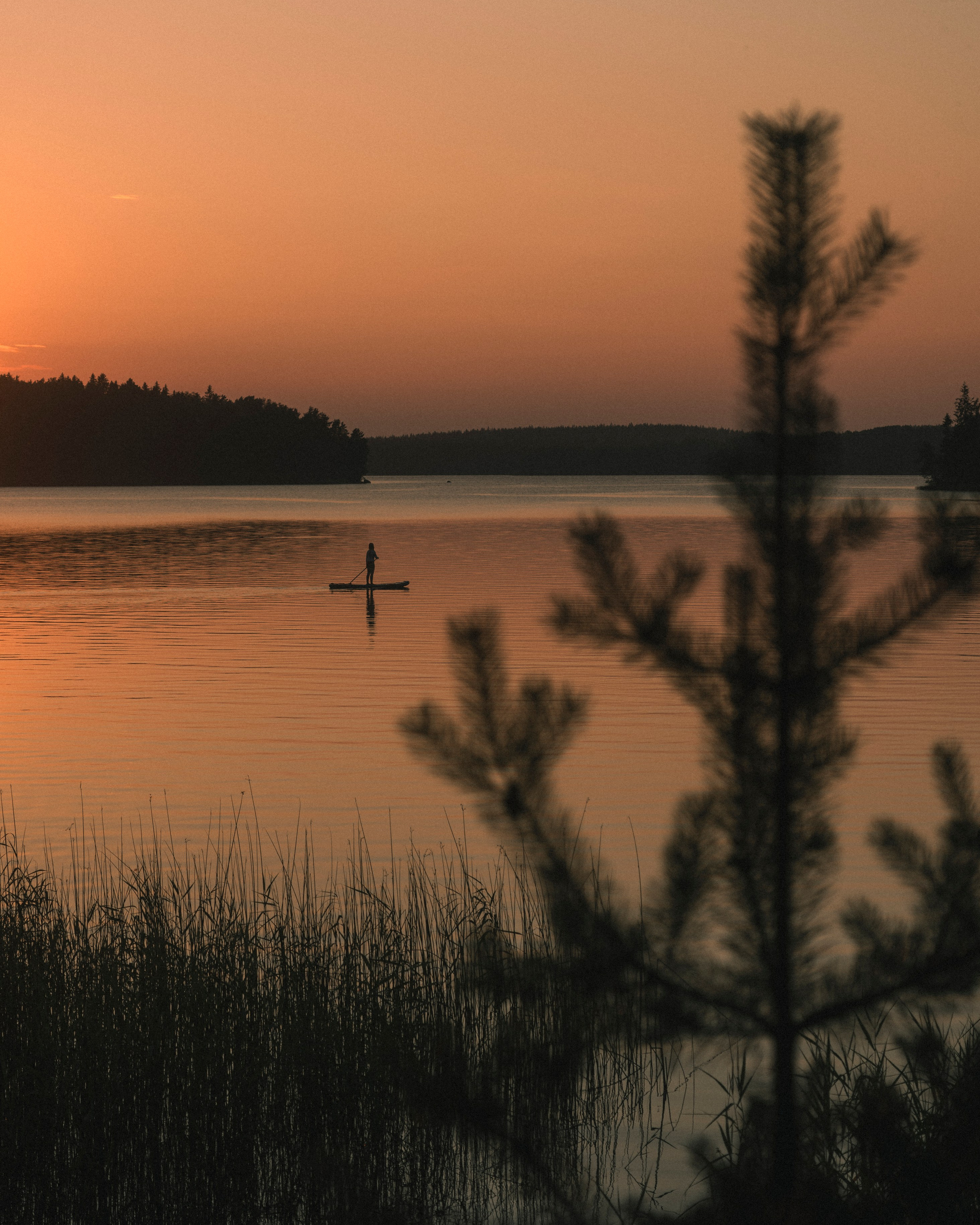 Пейзажное фото на берегу Зеркального озера с человеком плывущим на сапборде. 