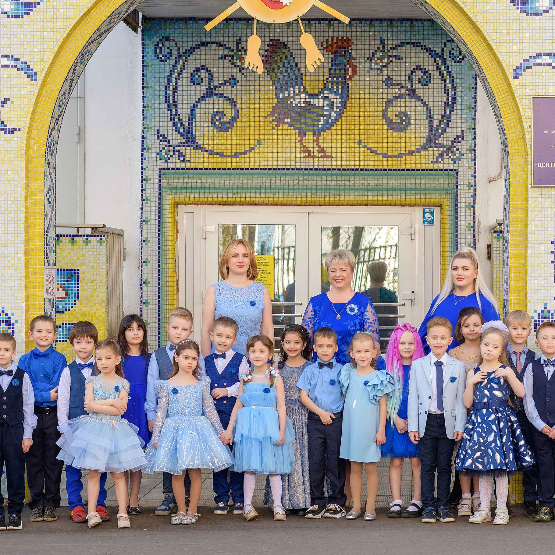 Групповая фотография на выпускном в детском саду. Красивая общая фотография у входа в детский сад. Группа детского сада на выпускной, одежда в синих тонах.