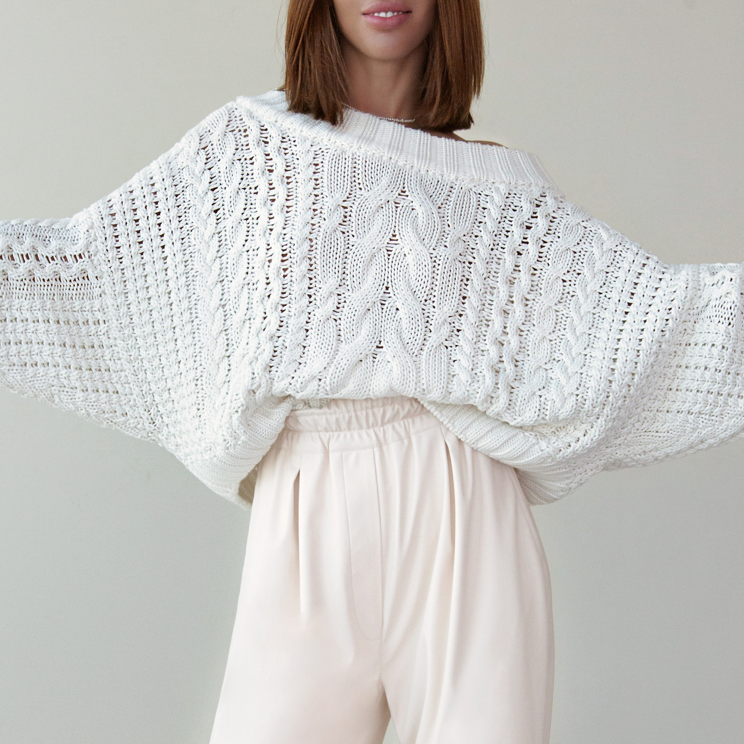 Модель девушка в белом свитере на фоне стены — съёмка одежды для маркетплейсов.