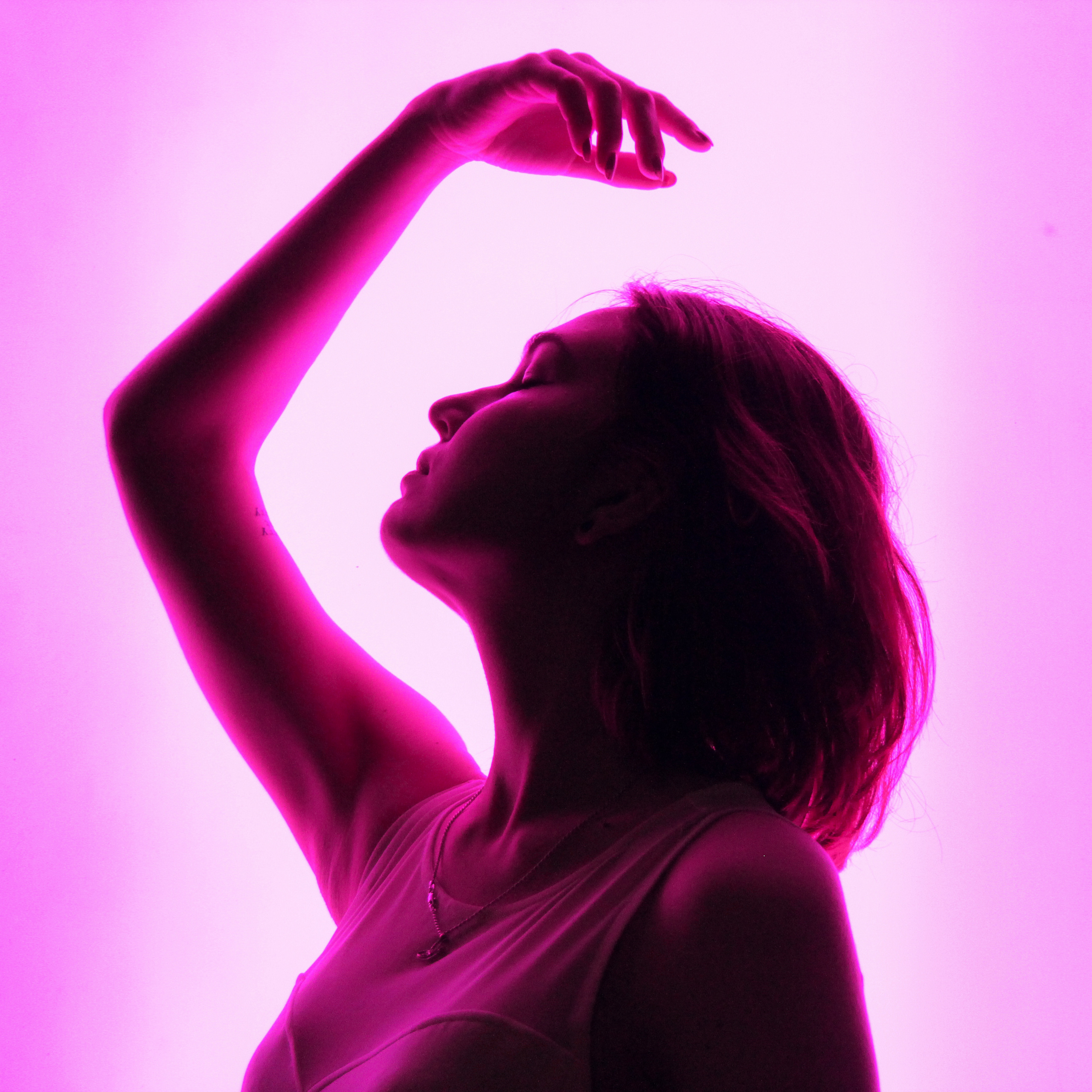 Девушка позирует в профиль на розовом неоновом фоне