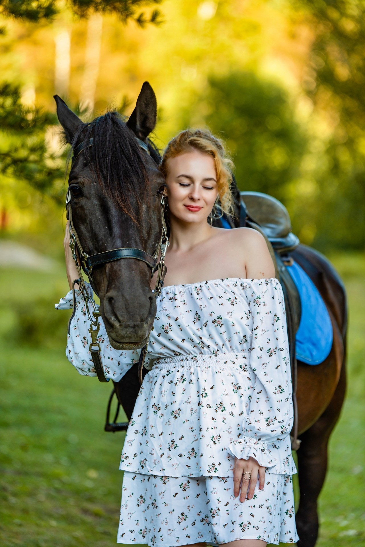 Молодая девушка в легком летнем платье обнимает коня