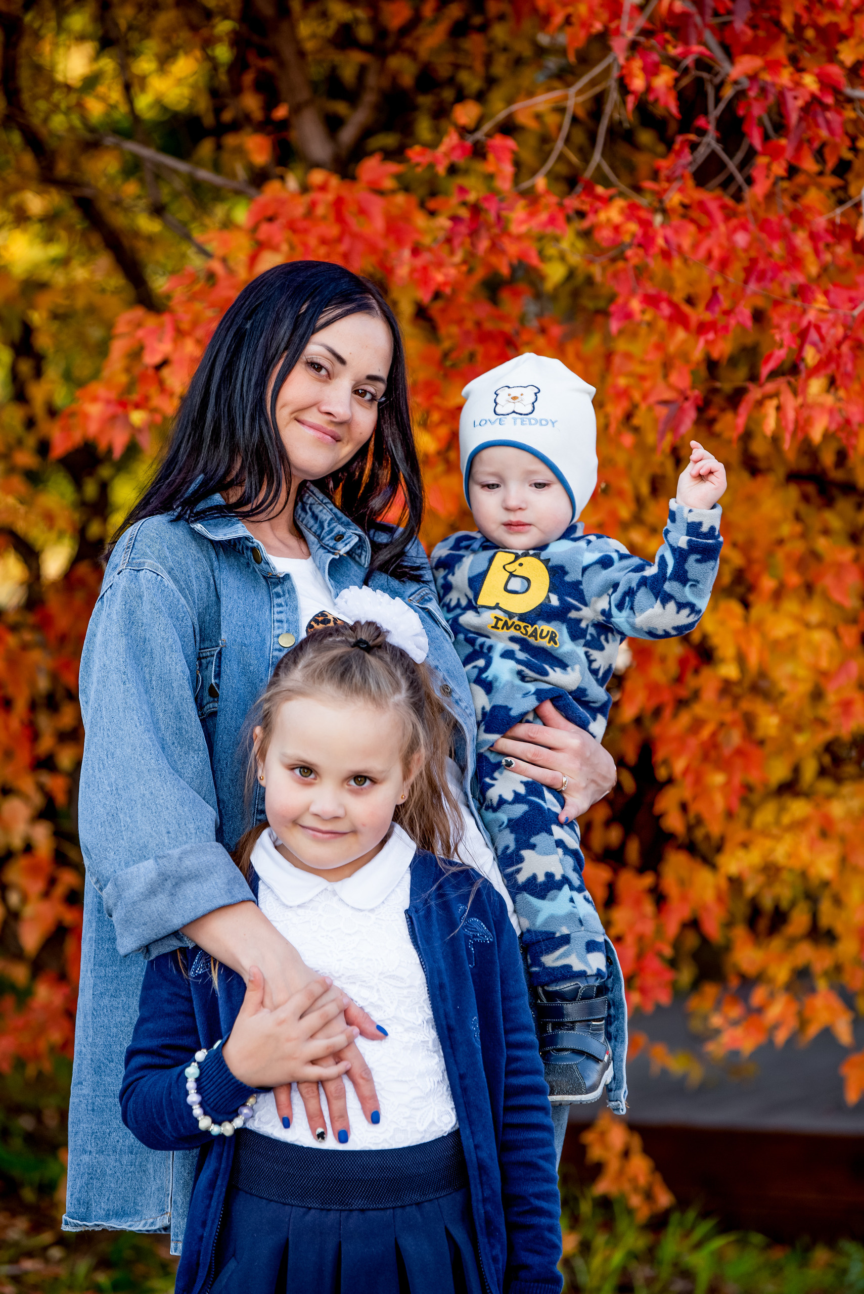 Мама с двумя детьми на прогулке осенью багряная золотая листва