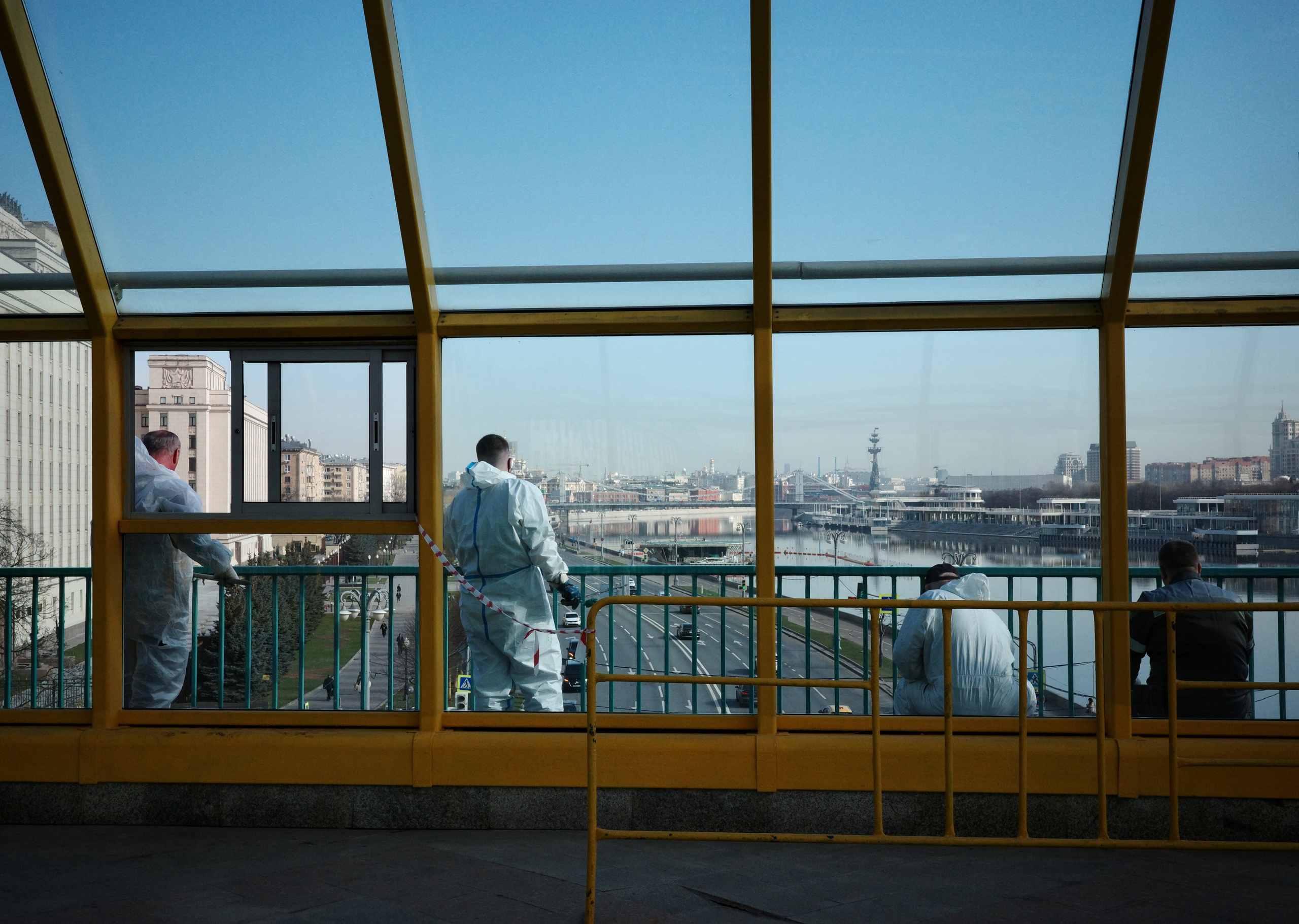 Рабочие в белых комбинезонах красят перила Андреевского моста, вид на Москву