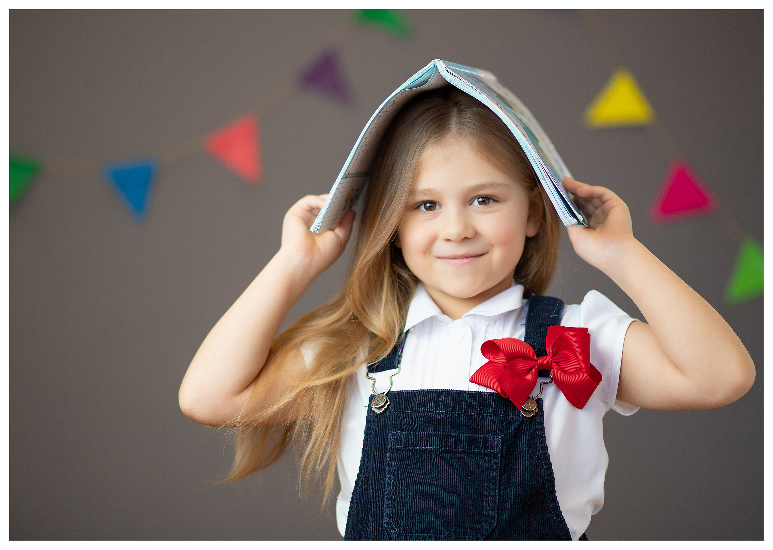 Девочка в школьной форме на смешной фотографии с книжкой на голове для альбома первоклассницы
