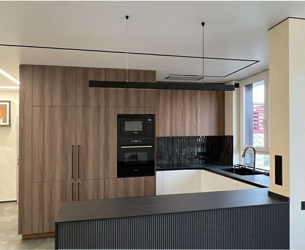 кухня-гостиная с древесными фасадами и графитовой кварцевой столешницей. Трековая система на потолке. линейный подвесной светильник над островом. 