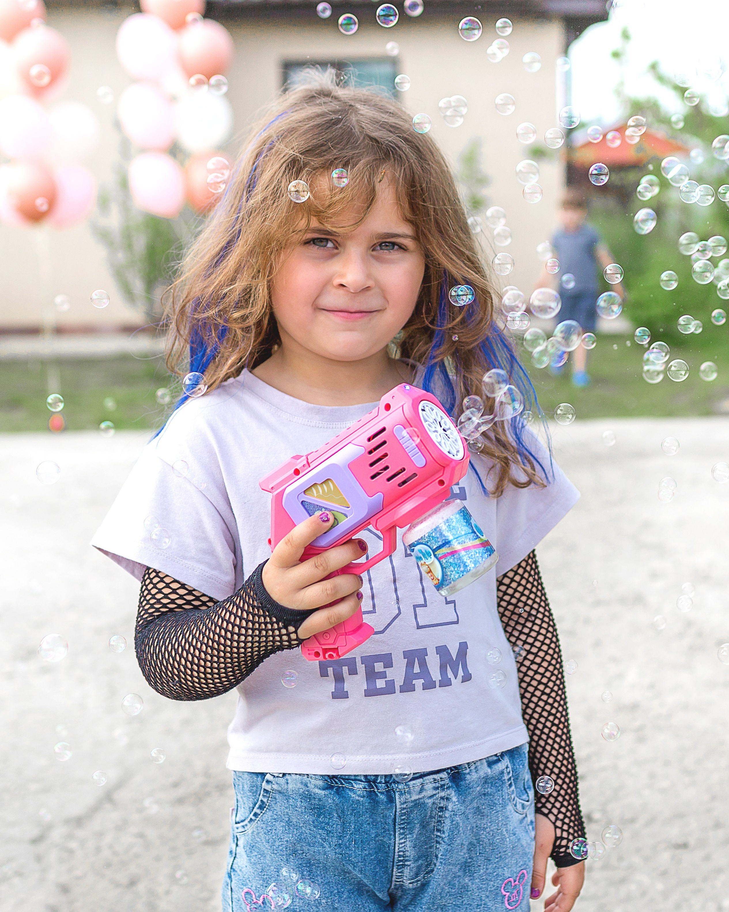 Девочка на улице стреляет мыльными пузырями