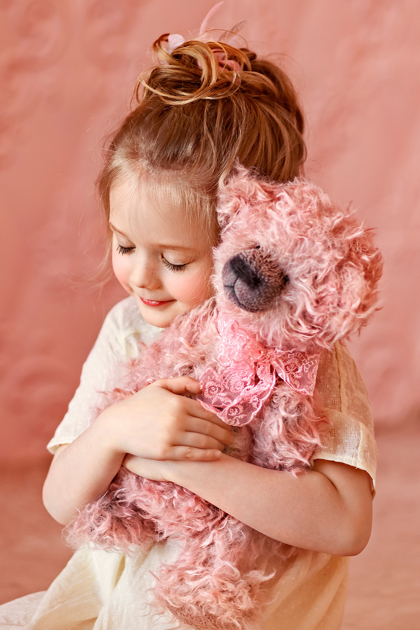 Девочка обнимает розового плюшевого мишку.