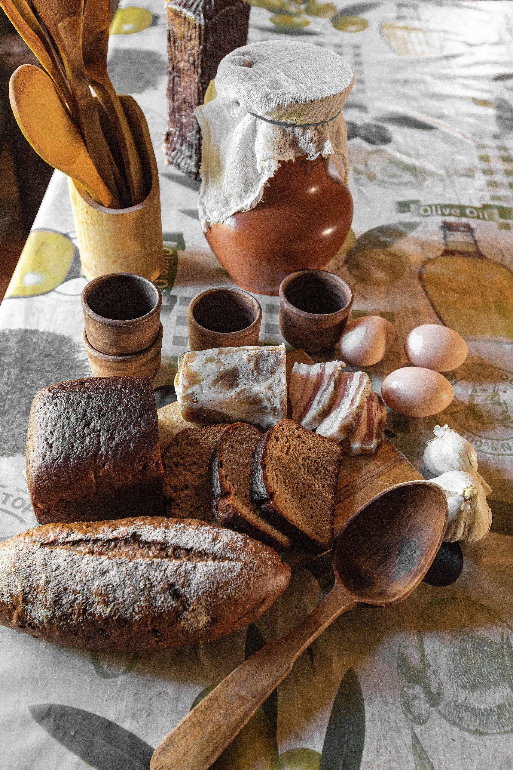 на доске черный хлеб,сало,чеснок,деревянные кружки и ложка