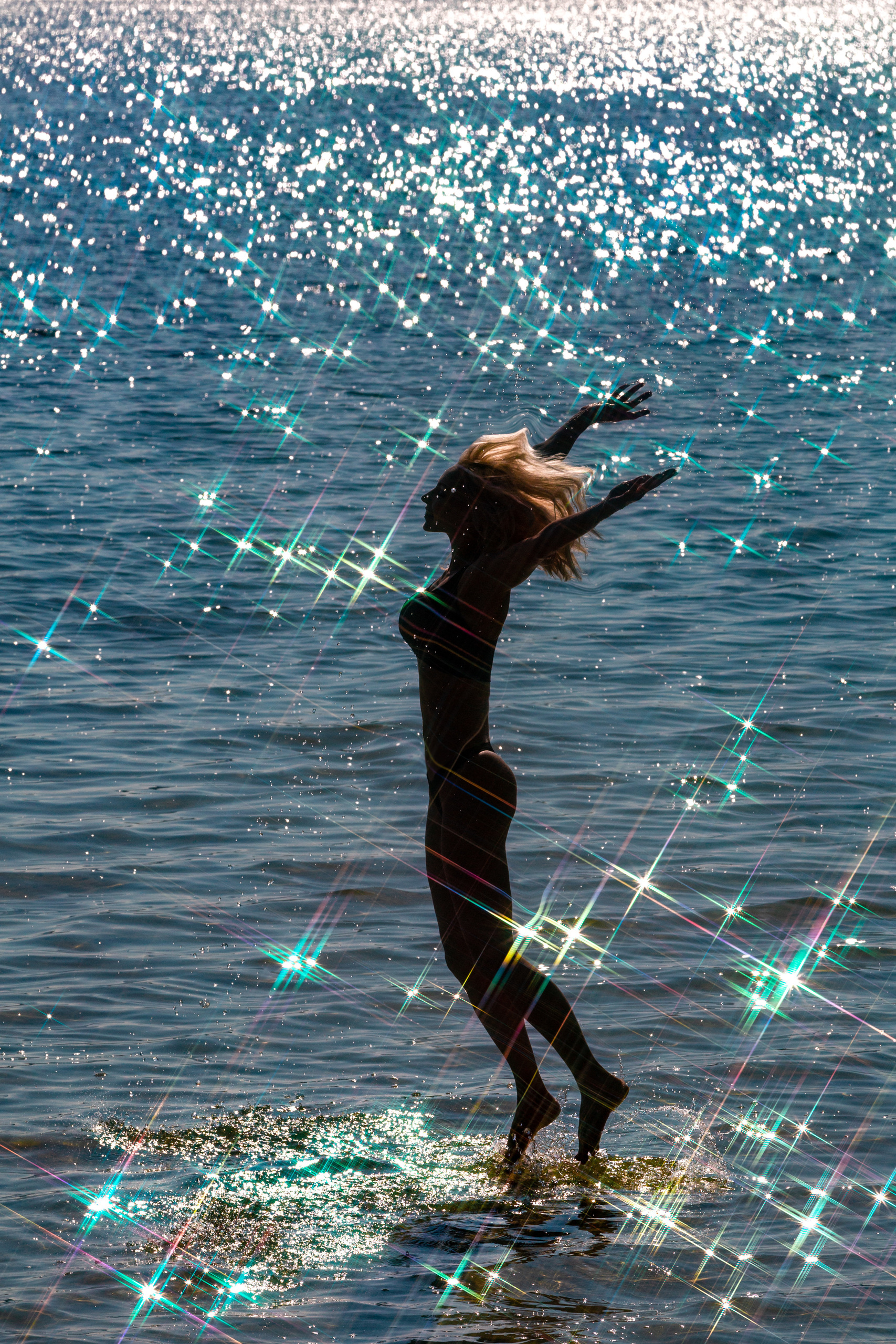 девушка в контровом свете прыгает над озером