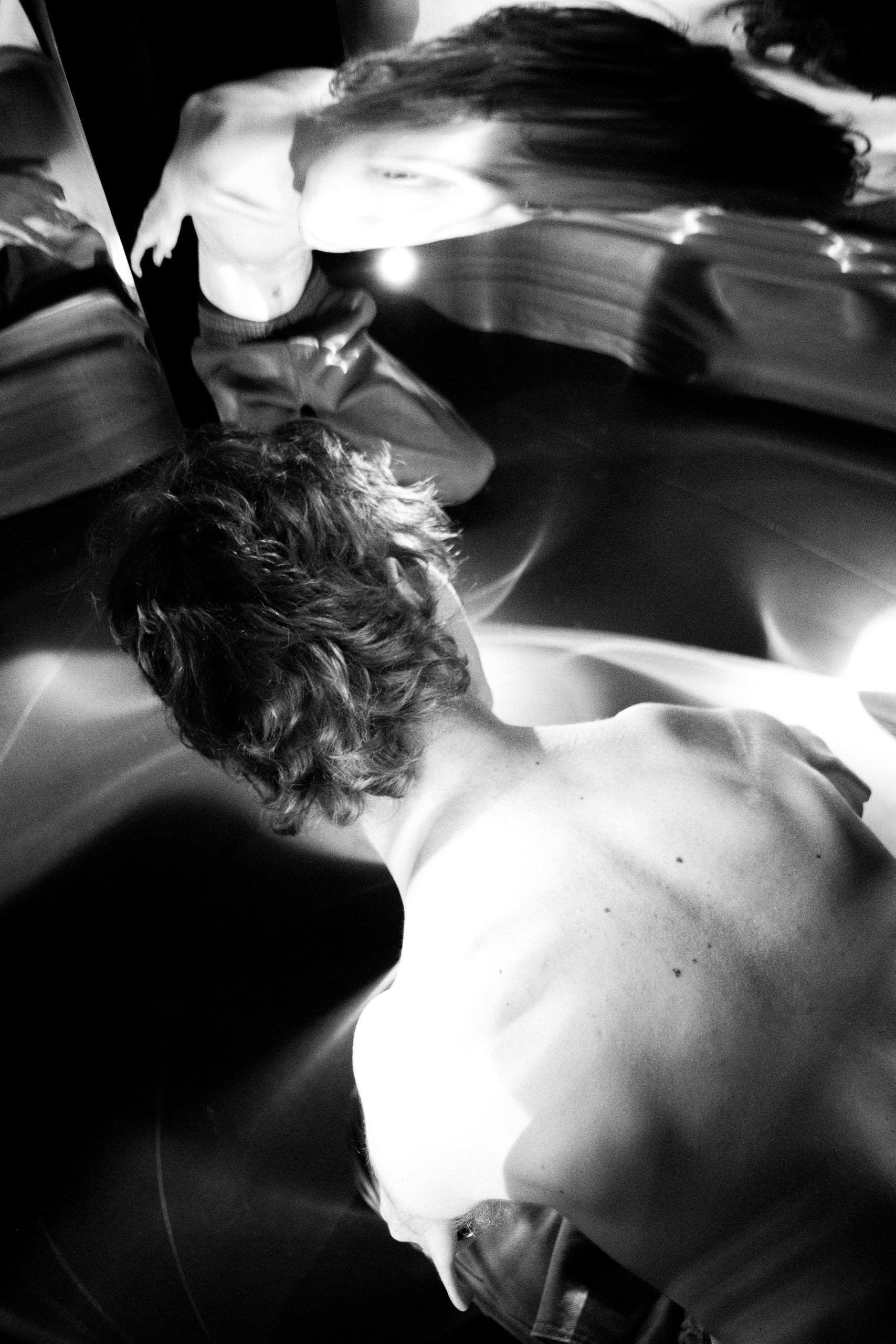 Abstract black and white photograph, distorted reflection of a male silhouette and a gaze into the camera