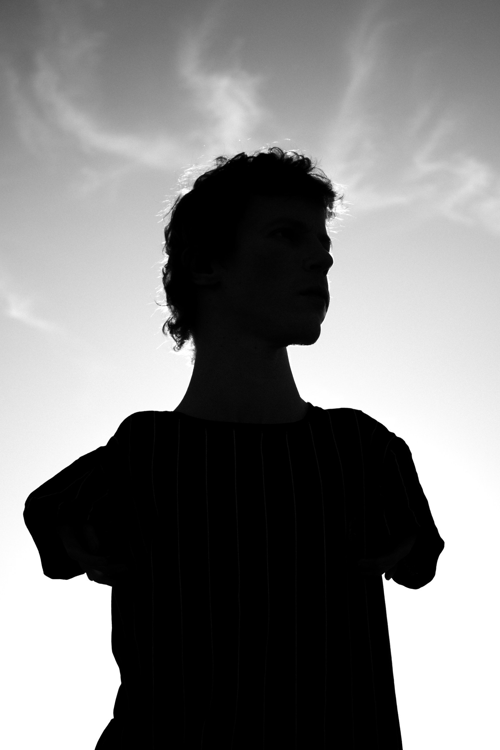 Black and white waist-length portrait of a man, minimalist silhouette in a t-shirt within backlit illumination
