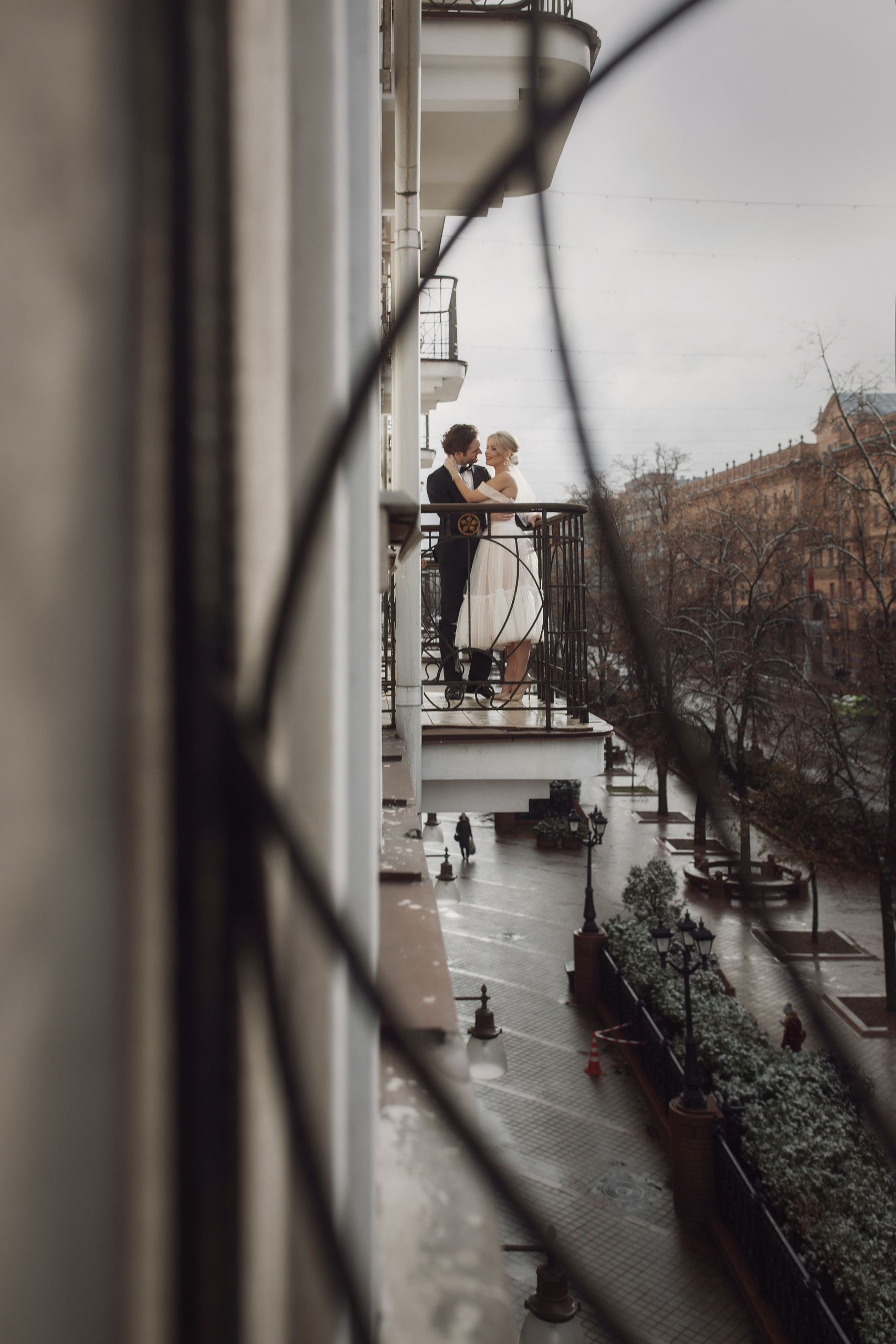 Пара молодоженов страстно целуются на балконе в номере отеля в центре города. 