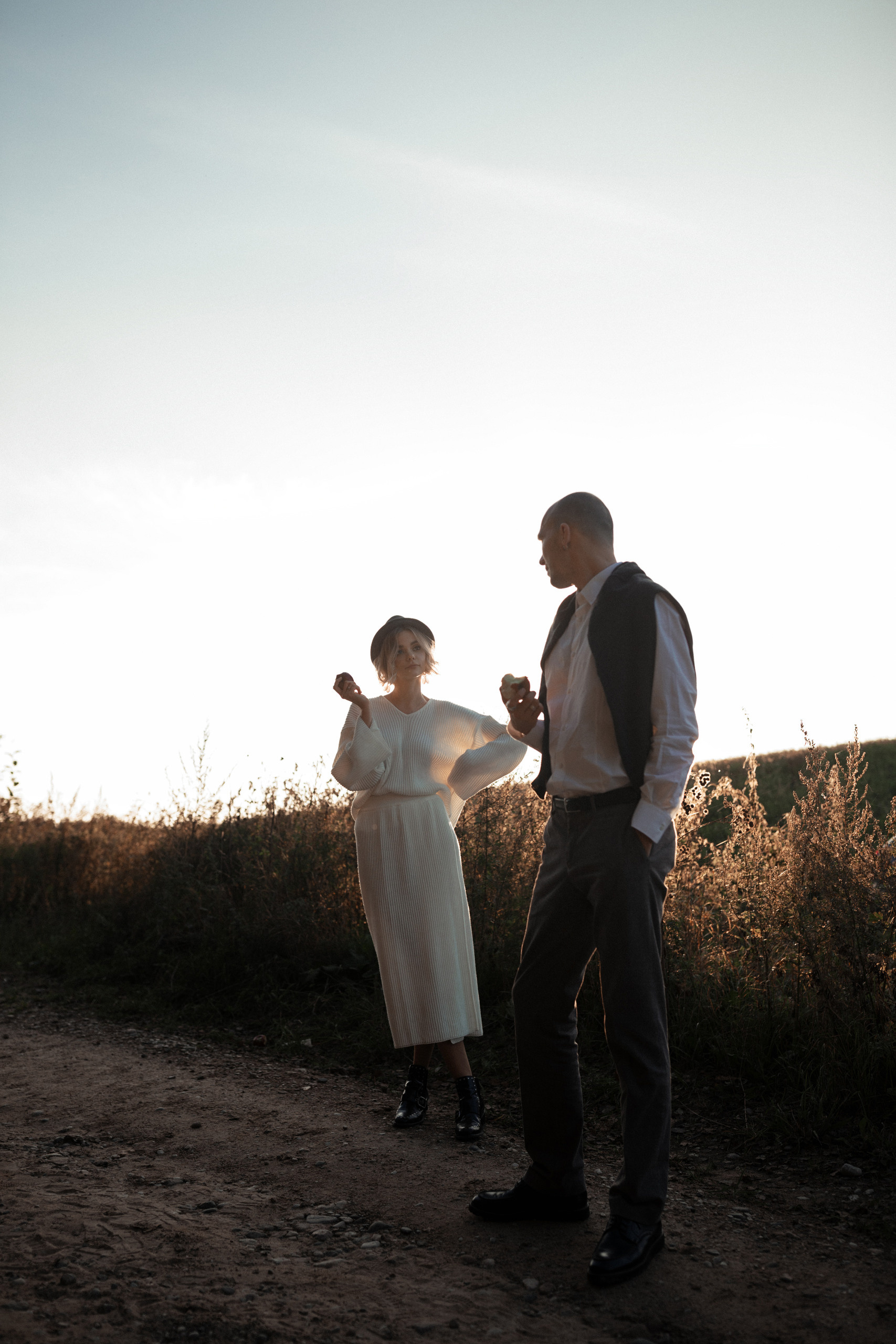 Стильные молодожены смотрят друг на друга.  В руках молодых яблоки, которые они с удовольствием уплетают.