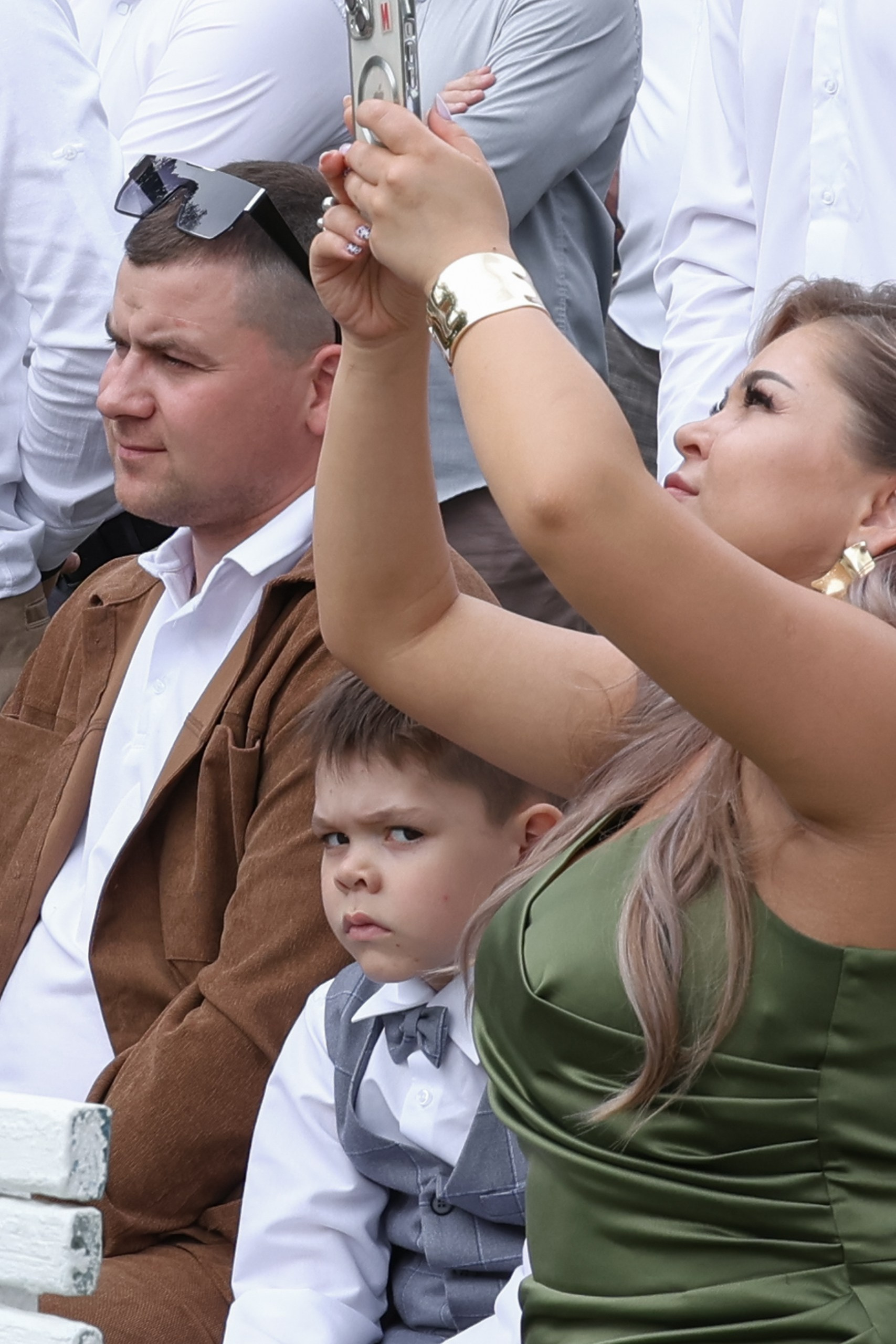 Мальчик с недовольным выражением лица сидит рядом с родителями