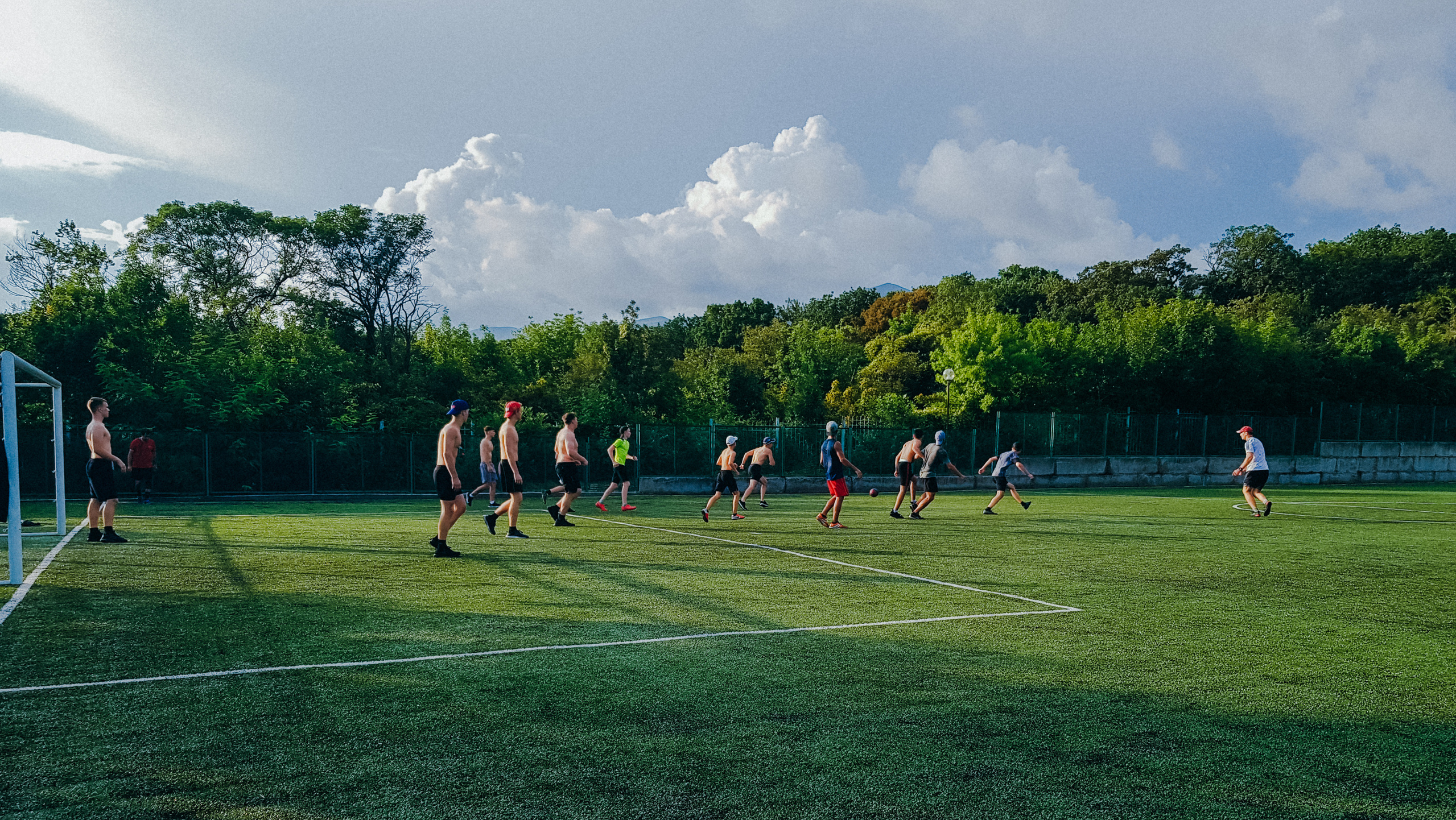 Футбольное поле, дети играют в футбол на фоне зеленого леса