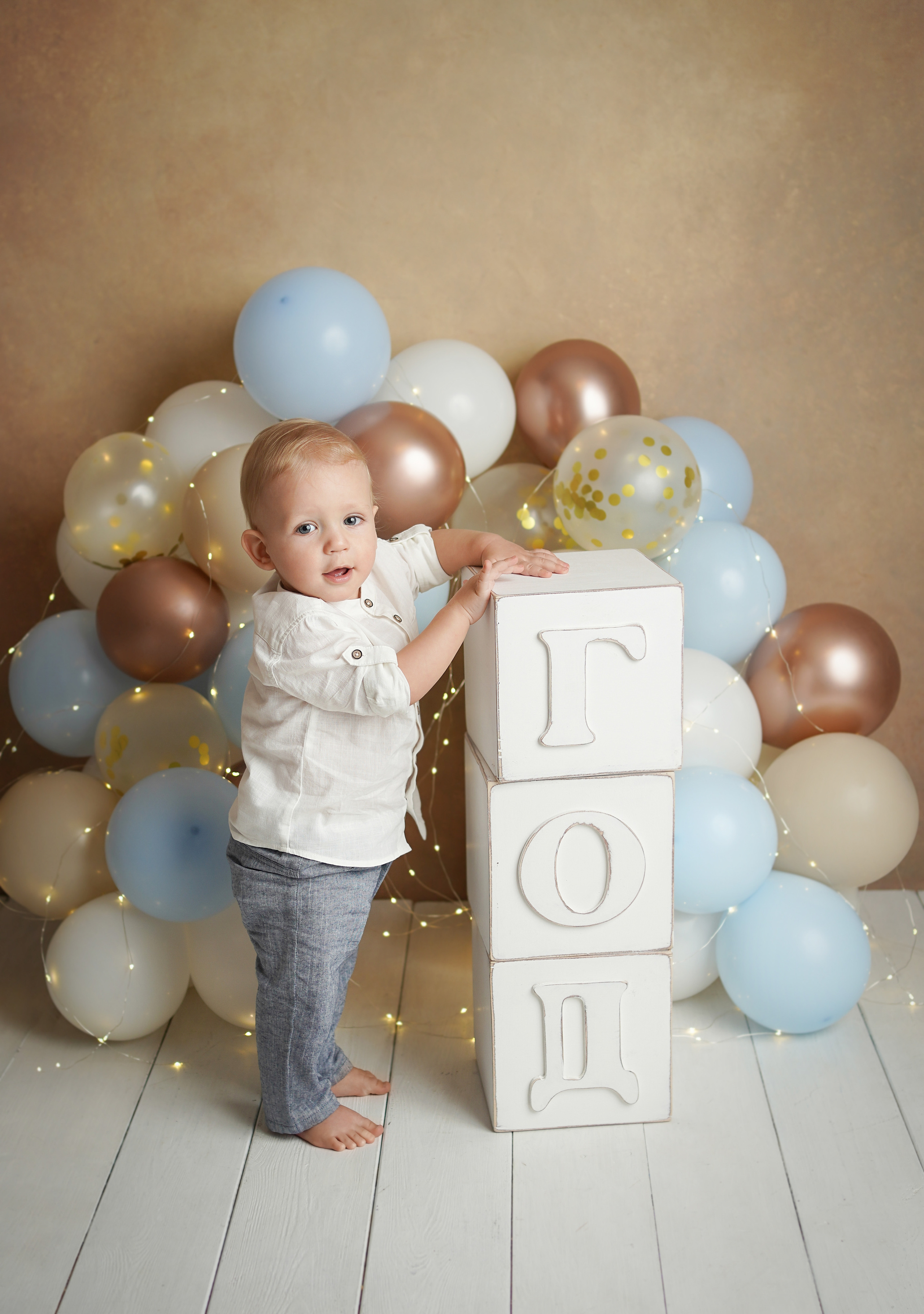 Малыш в нарядной одежде стоит рядом с большими кубиками с надписью Год.