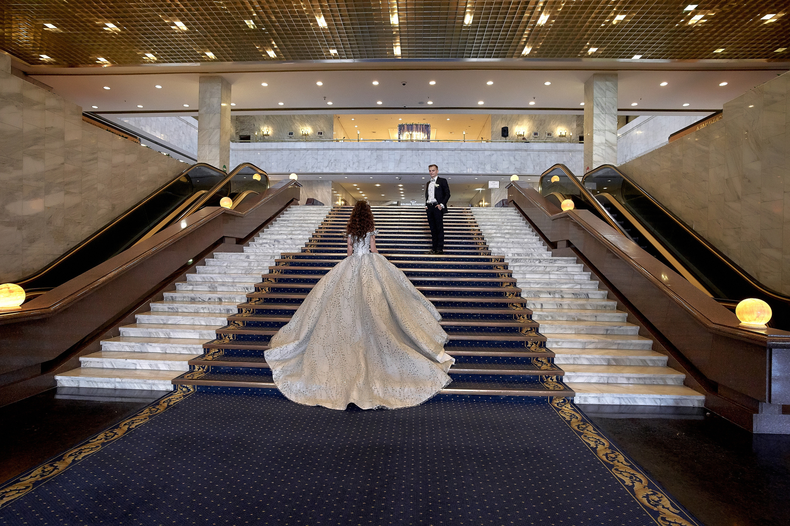 Невеста поднимается по широкой лестнице Президент отеля. Ее встречает жених.  Свадебный фотограф Сергей Гаварос. Свадебная фотосъемка в Москве