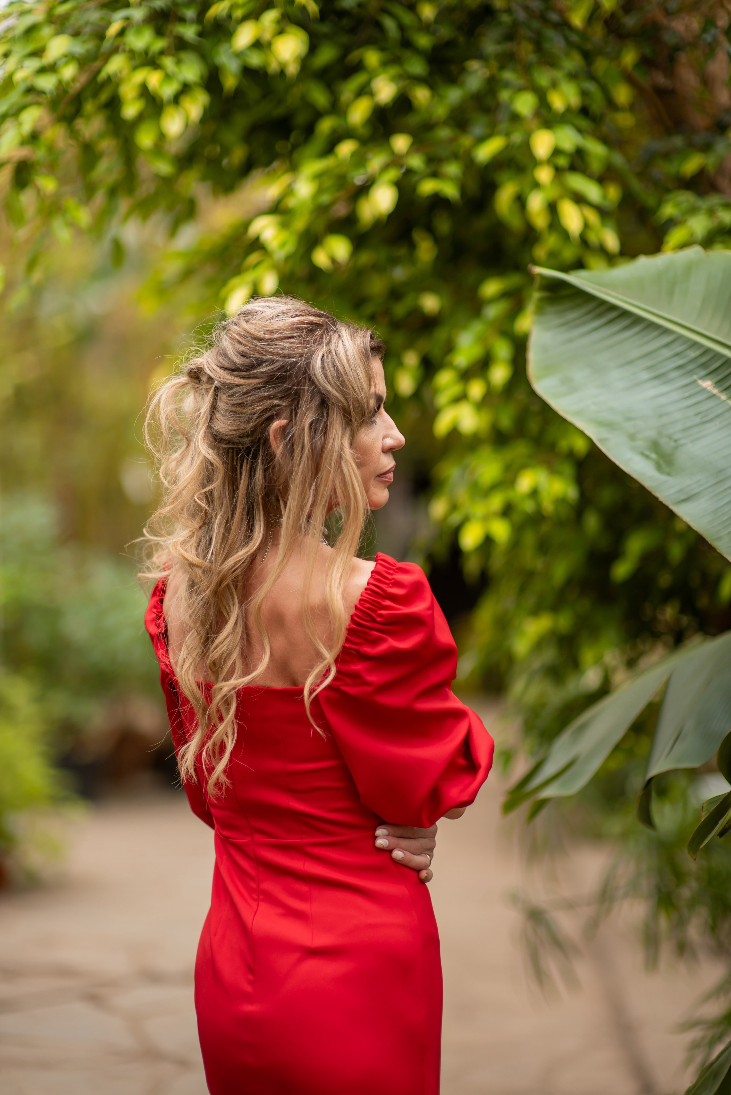 Девушка в легком летнем платье сидит на скамейке в тропической зелени фотосессия