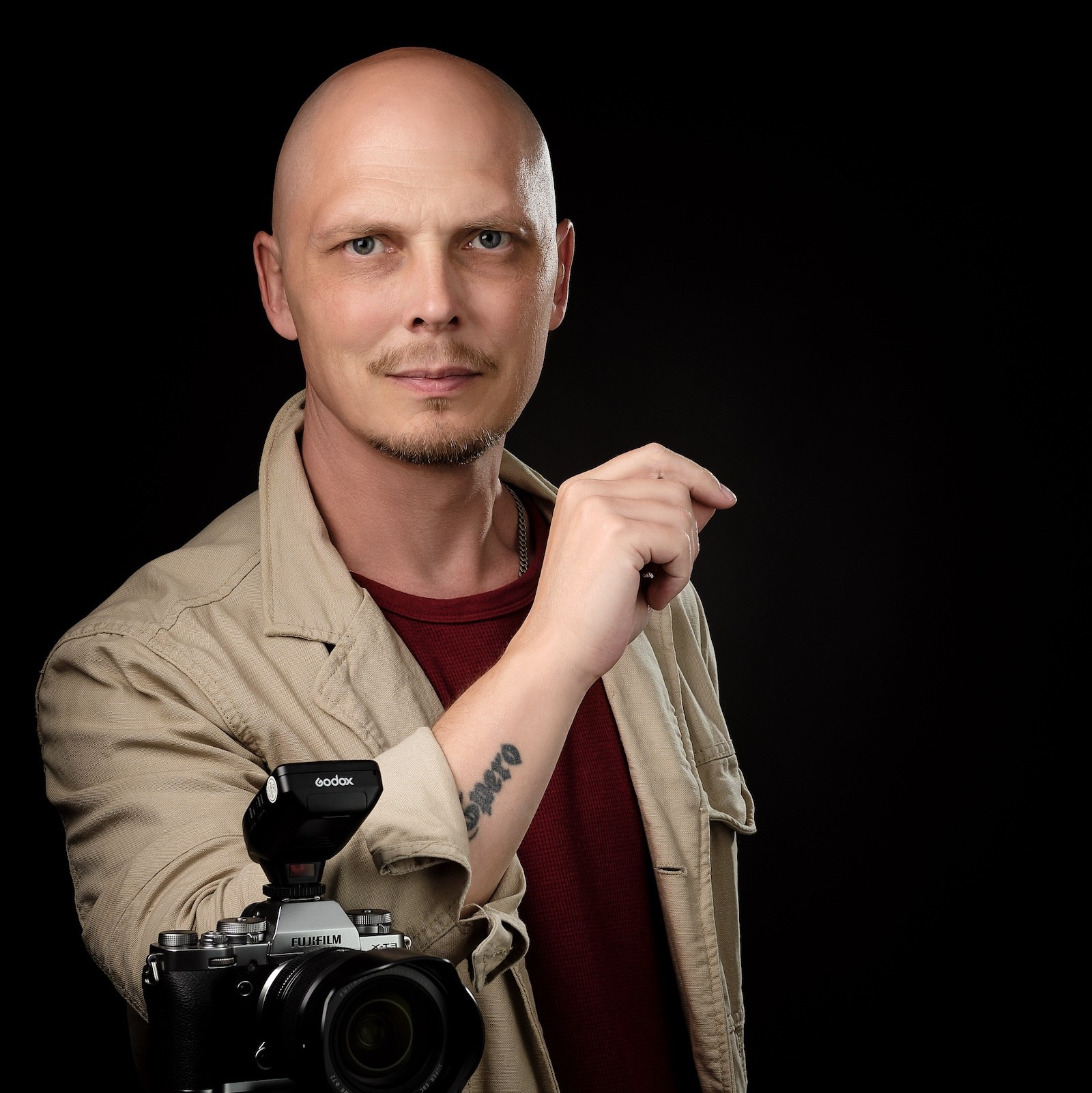 Портрет Дмитрия Лукьянова с камерой в руках на чёрном фоне — преподаватель курса