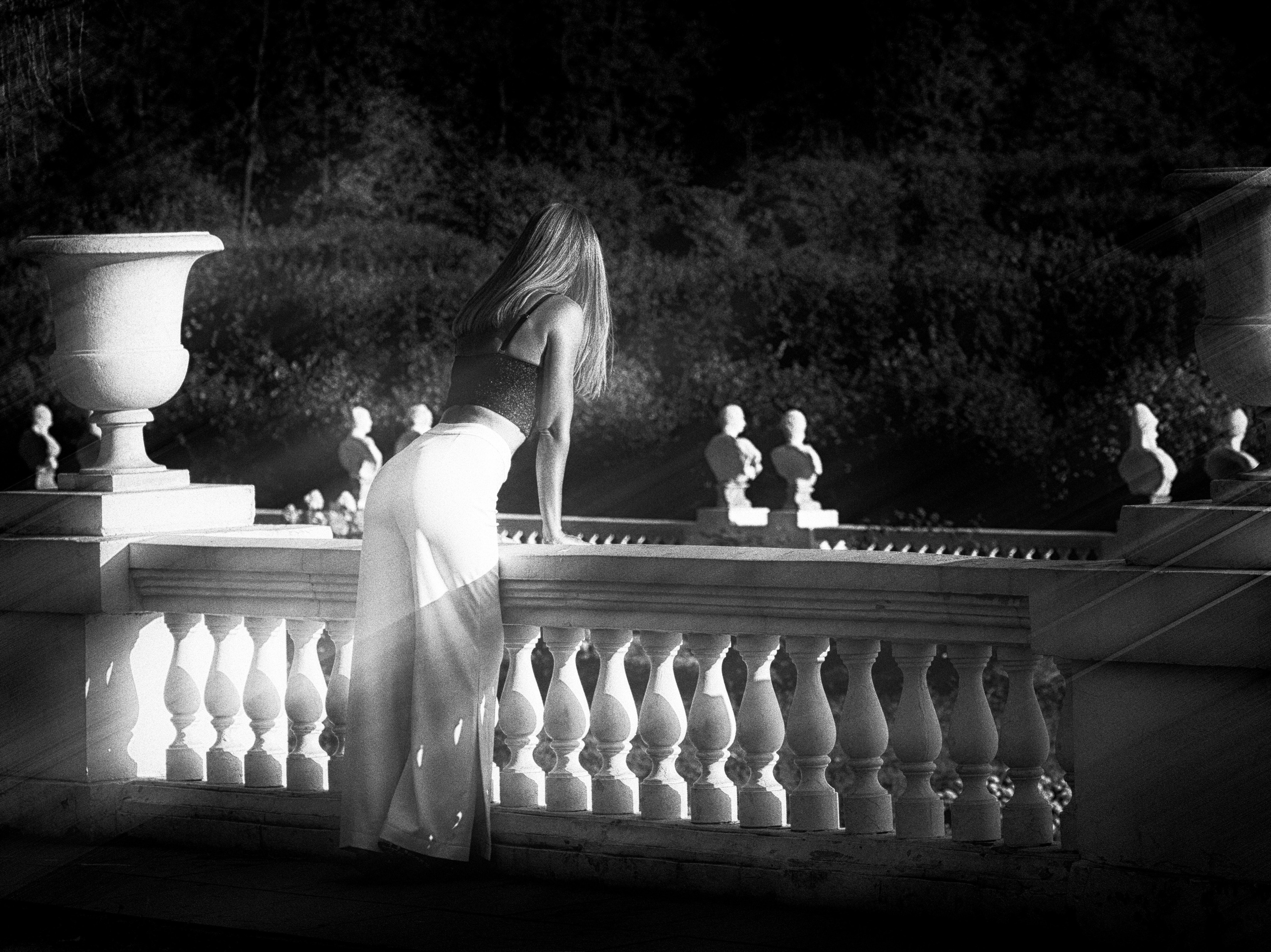 Шикарная женщина в корсете смотрит вперед опираясь на балюстраду.