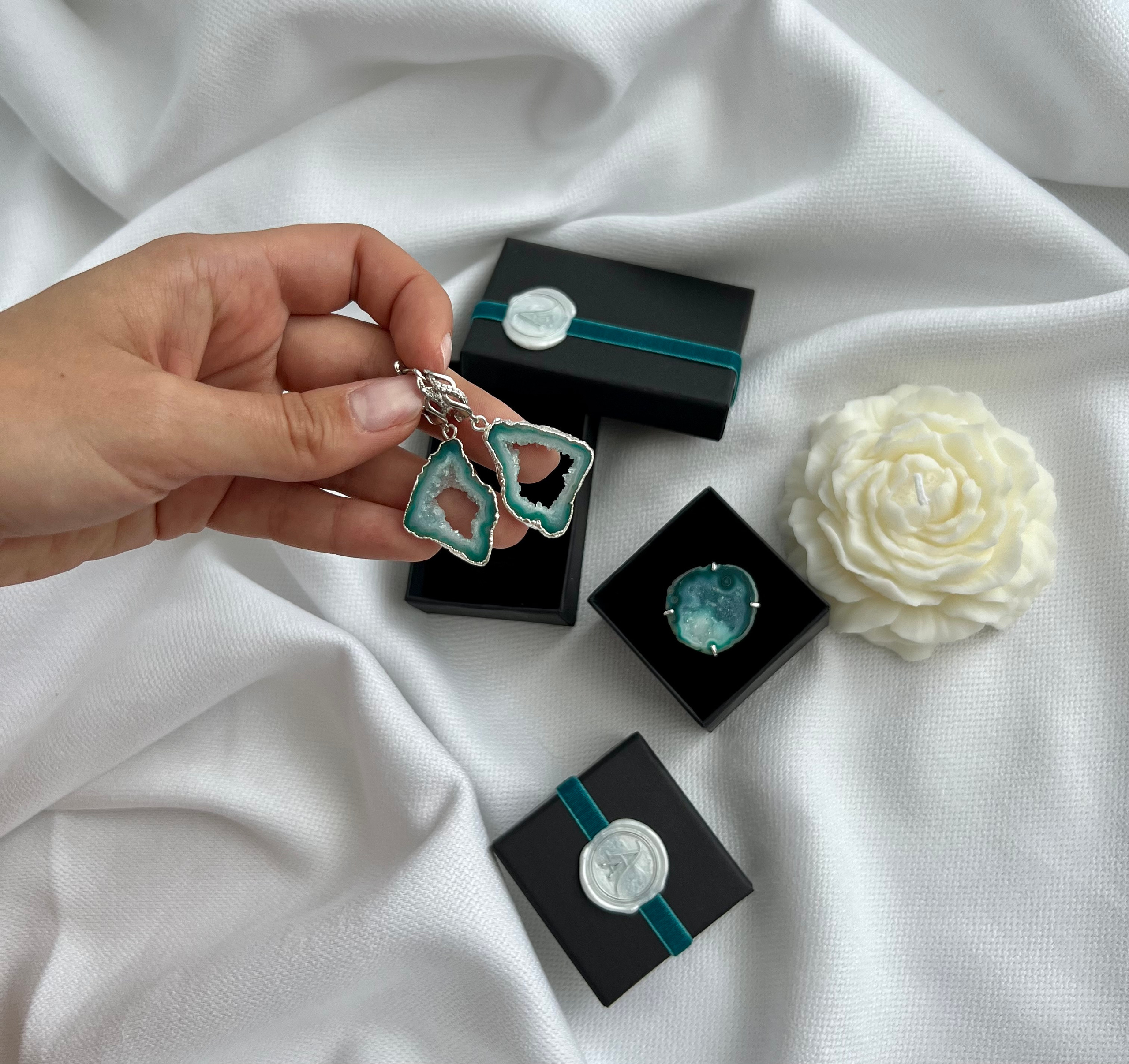 Набор бирюзовых сережек из натуральных камней рядом лежит свеча виде цветка