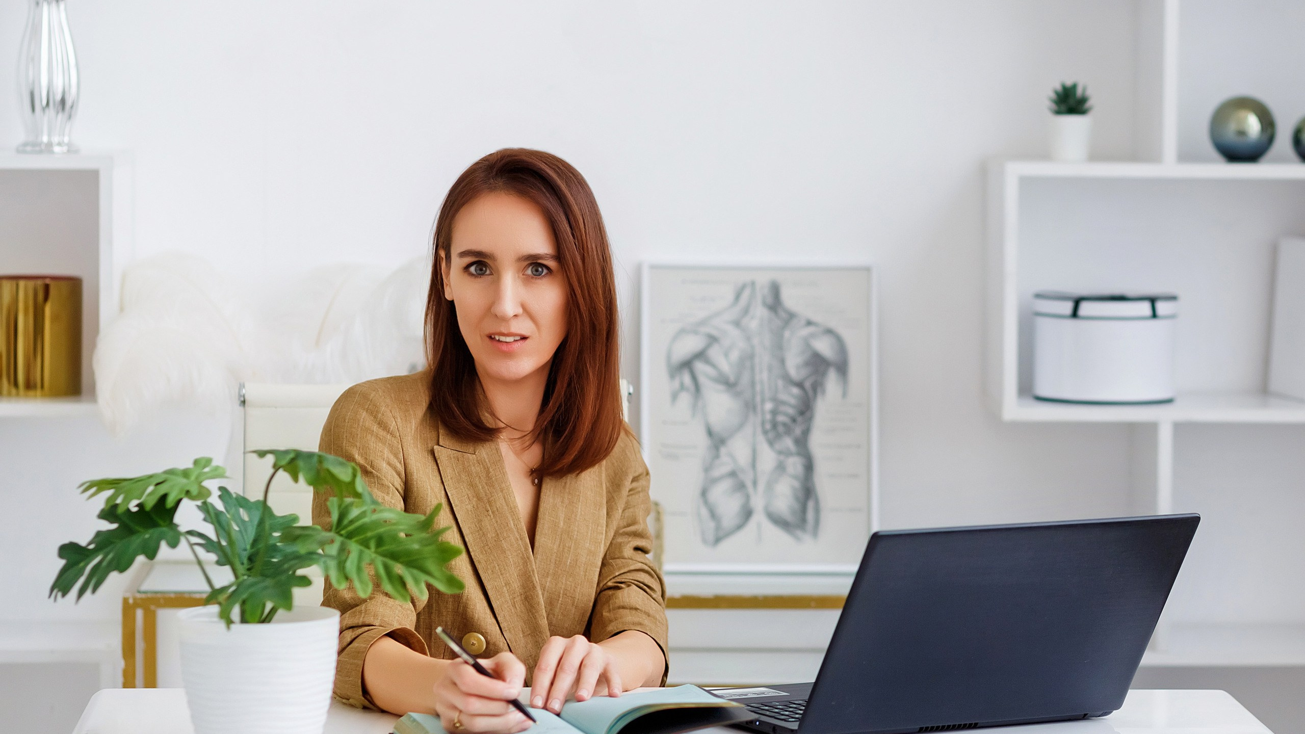 Нутрициолог девушка в пиджаке на светлом фоне с ноутбуком в руках 