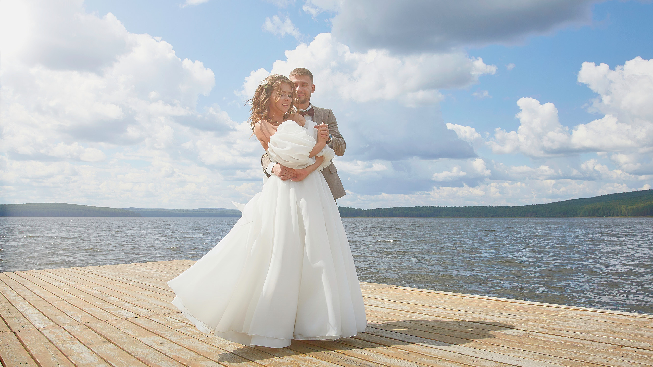 Романтический танец молодоженов на пирсе на фоне воды