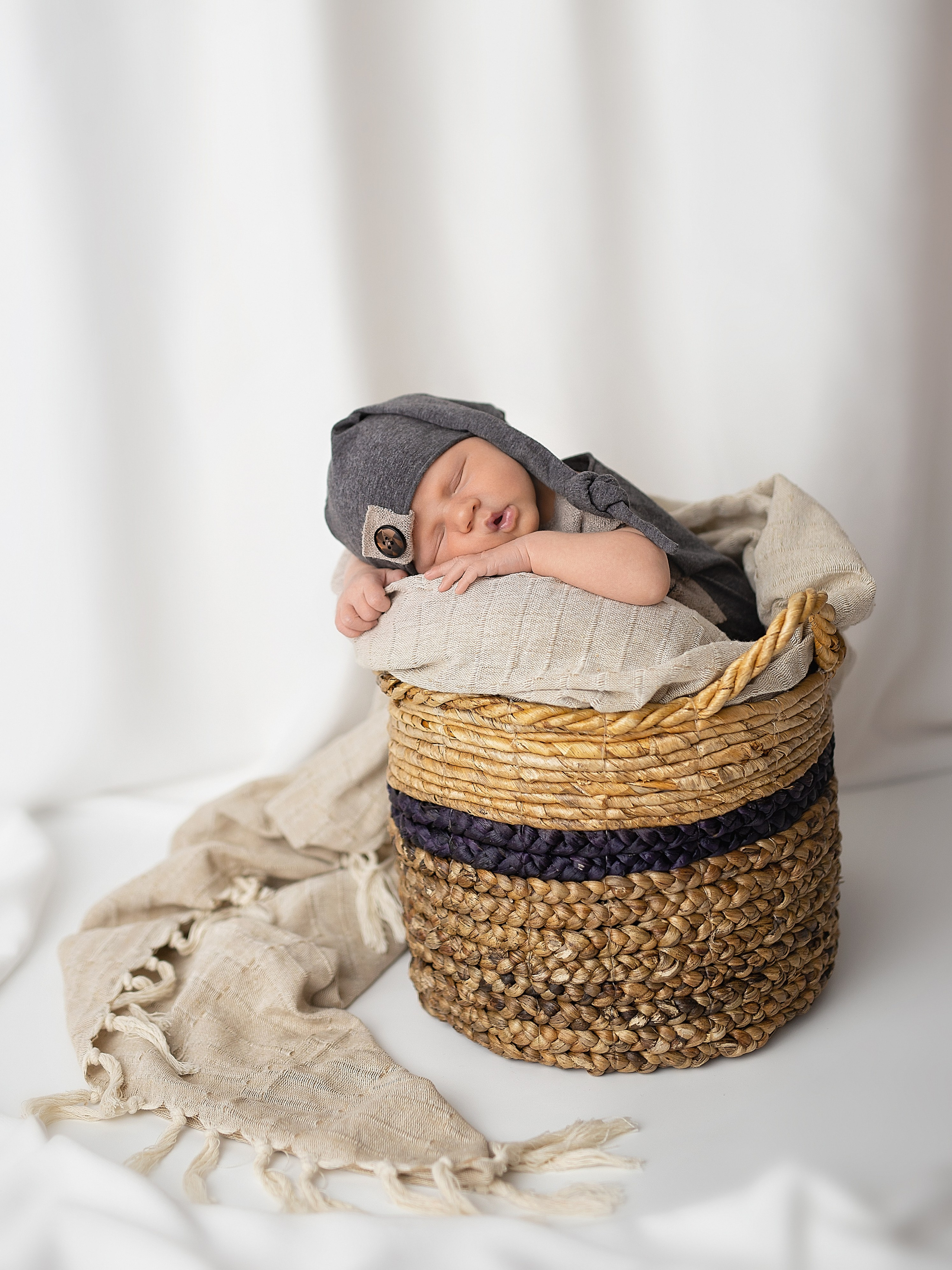 Новорожденный лежит на животике в корзине на белом фоне