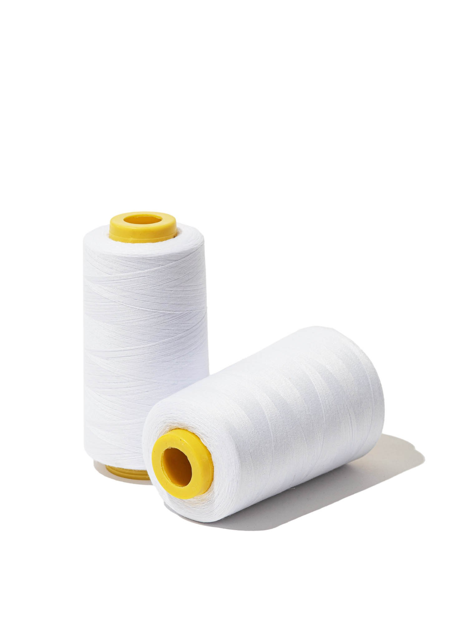 Белые нитки на катушках — крупный план, детали для товаров в сфере шитья и рукоделия.