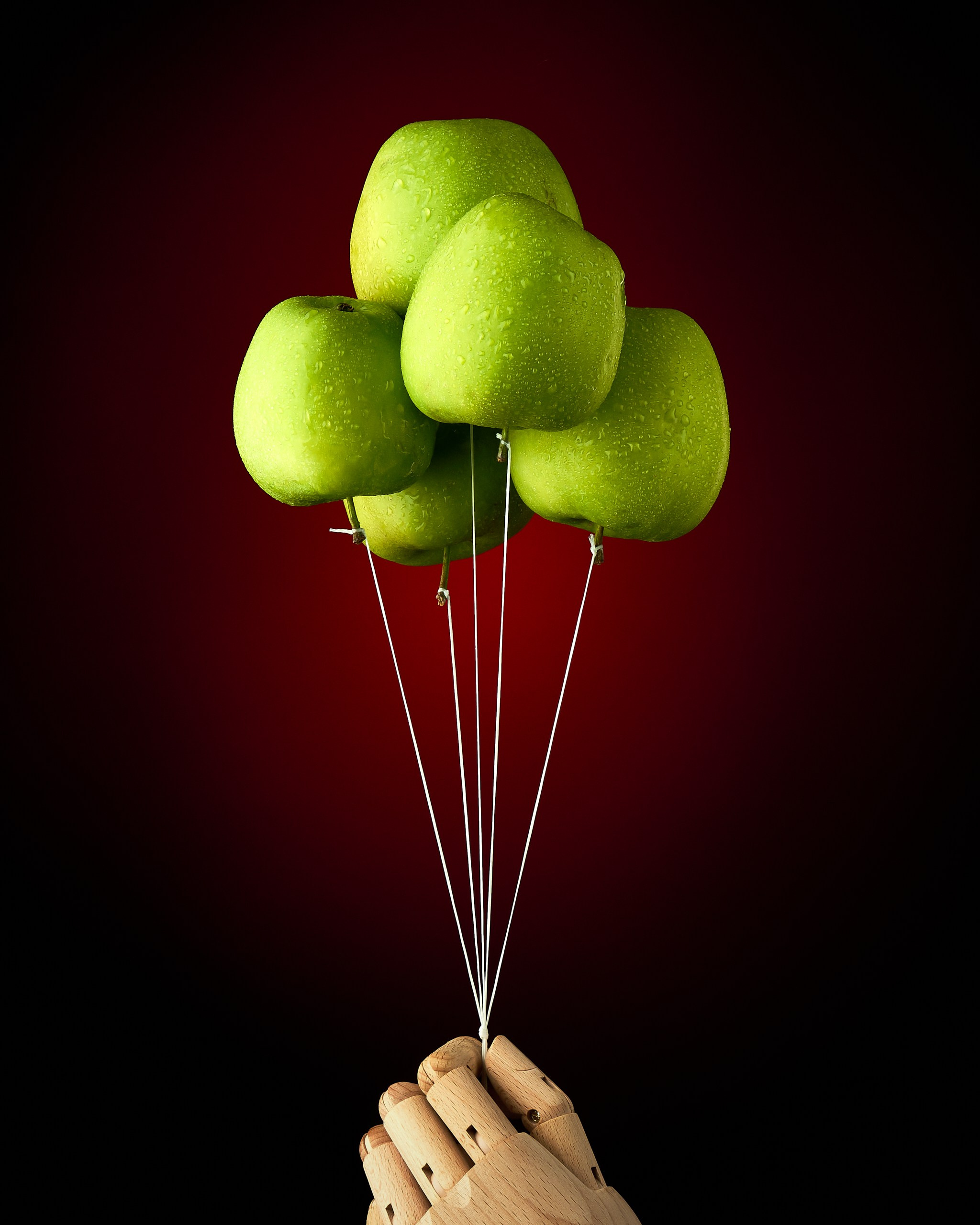Зелёные яблоки, закреплённые на нитях, на красном фоне, серия CONTAINMENT, авторская арт-фотография