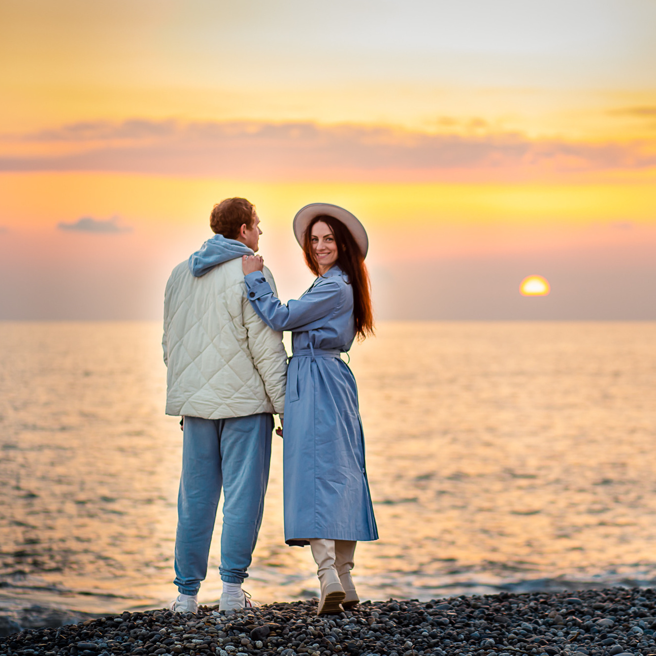 Красивая молодая пара на фоне солнечного заката на берегу моря