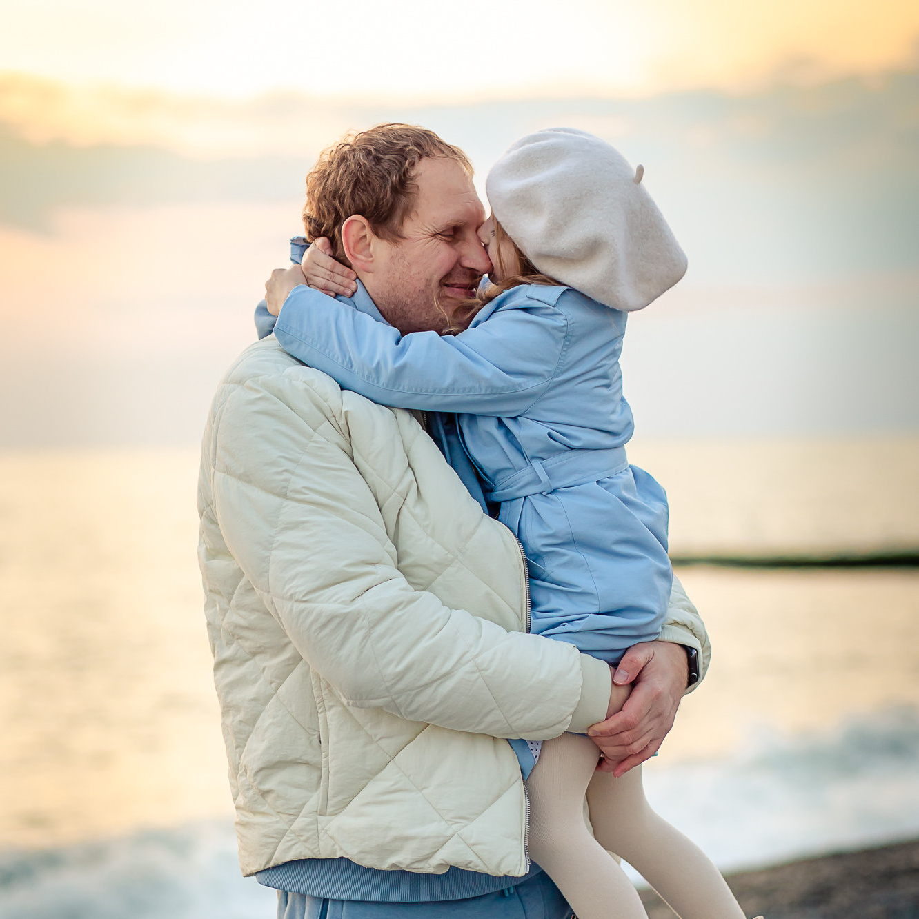 Папа с дочкой на фоне моря с закатным солнцем