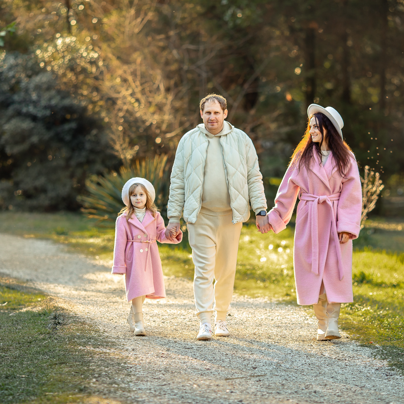 Красивая семья гуляет в парке в розовом пальто