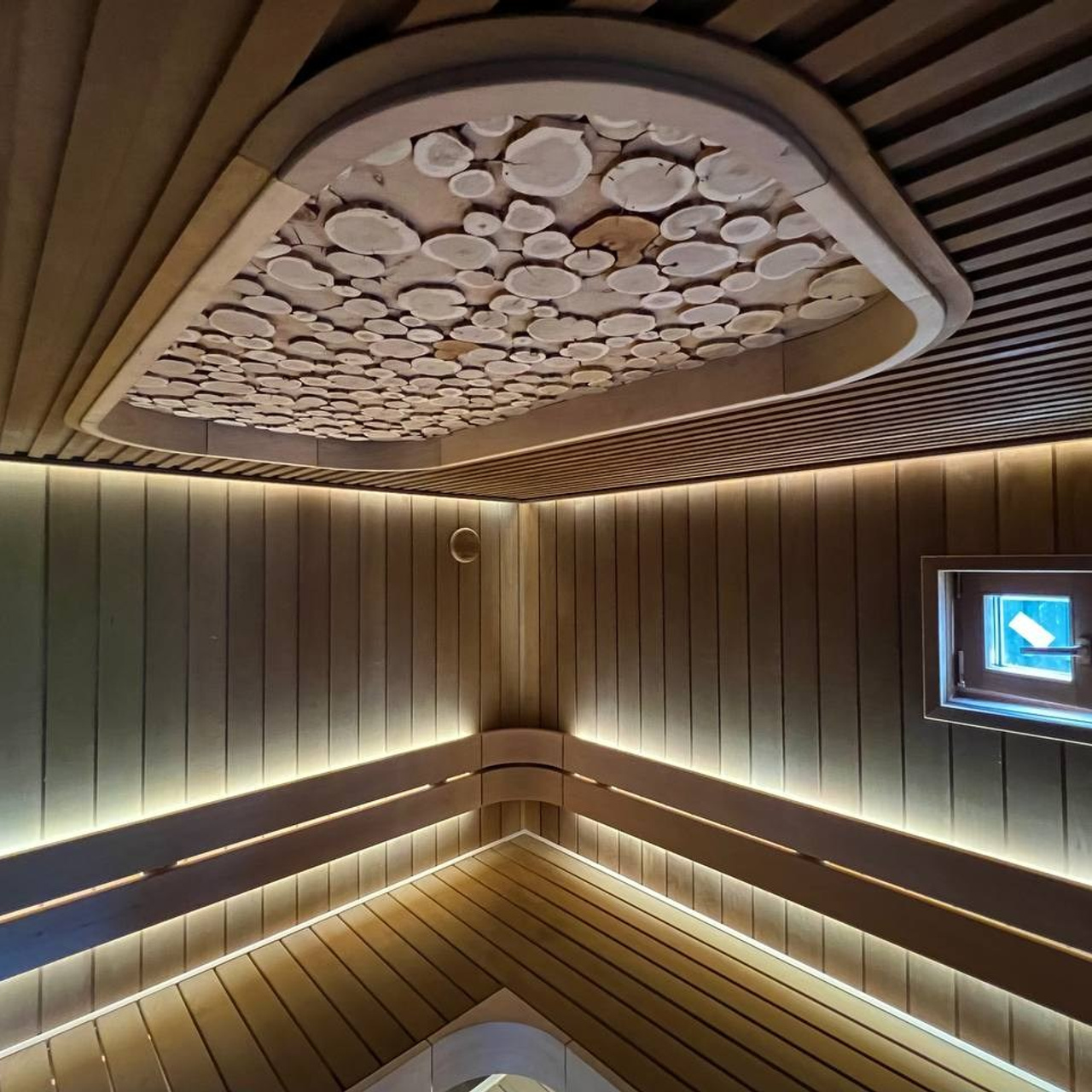 Парная в Колосе по индивидуальному проекту с реечным потолком, плавными линиями радиальных элементов и теплой закарнизной подсветкой