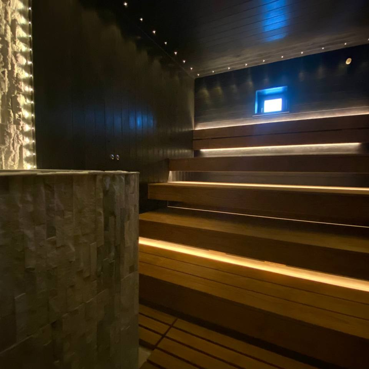 Чёрная «Богатырь-баня» в Боровске: четыре уровня полков, белый кварцит в противопожарном углу и кастомная газовая печь в центре внимания.