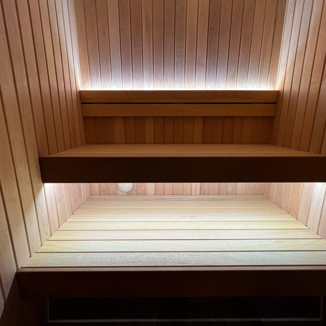 Компактная сауна для двоих на Переправе в отделке из ольхи, абаши и белого кварцита. Жар задаёт Harvia Cilindro