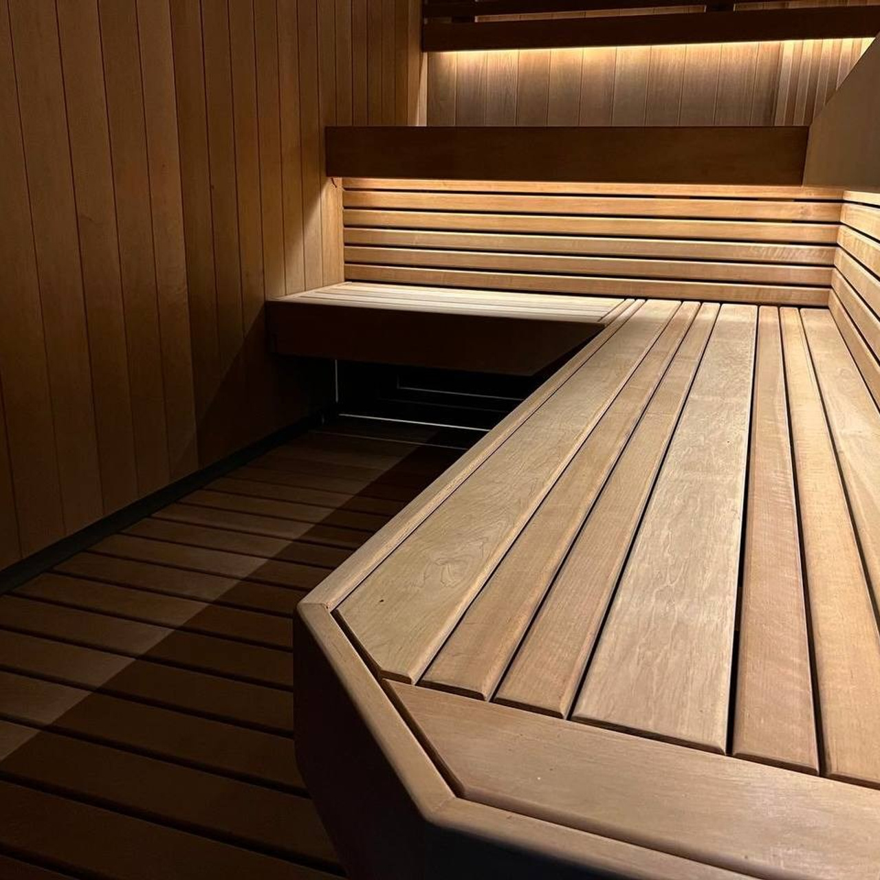 Сауна в Керро из разноширокой термоольхи. Ламповый свет термостойких лент и закарнизная подсветка плитки из талькохлорита 300×300мм