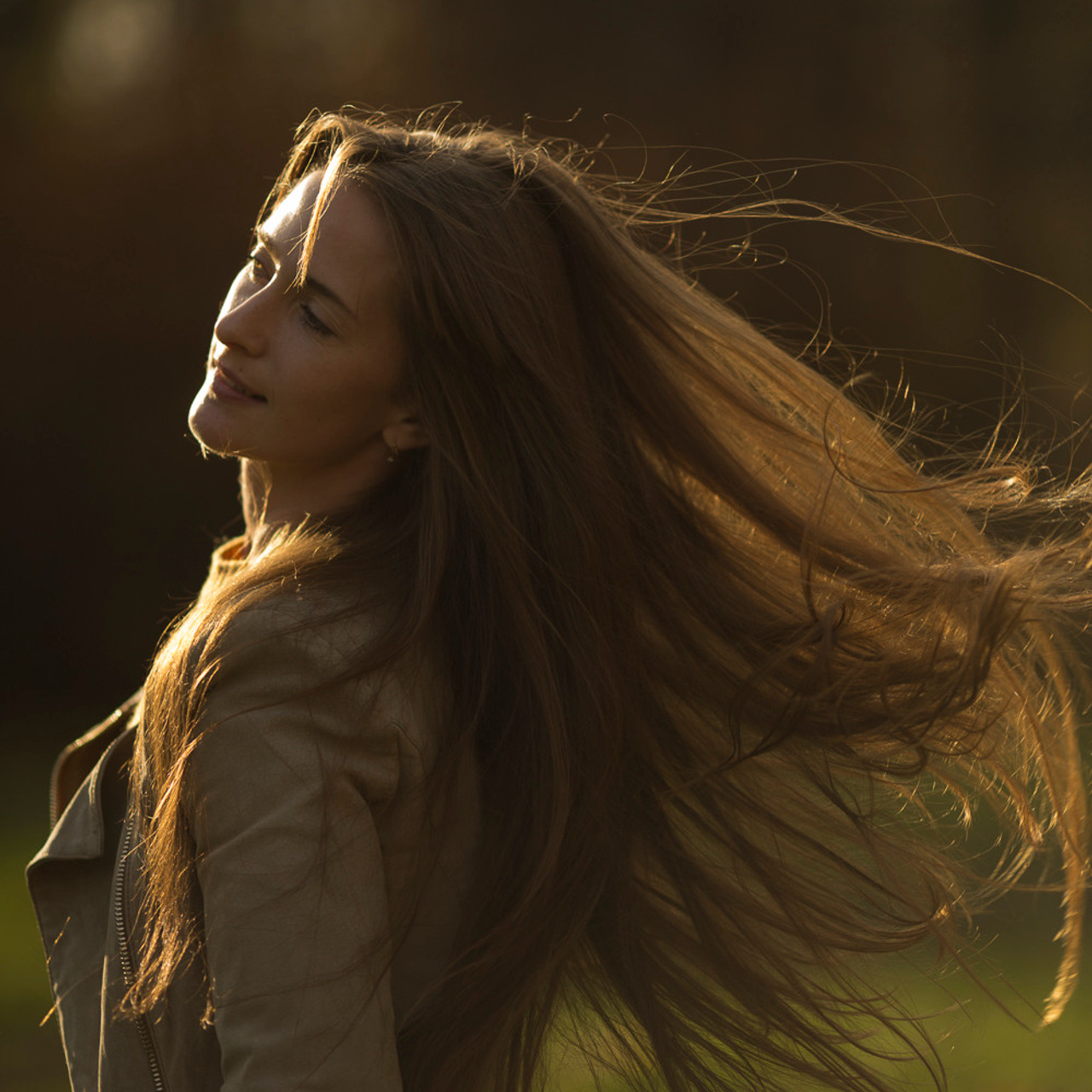 Фотопортрет девушки в контровом закатном свете в парке в Санкт-Петербурге, ее волосы красиво развеваются на ветру