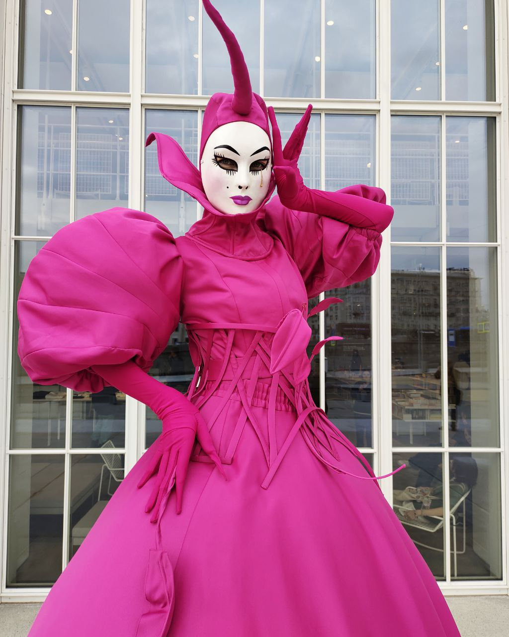 Мим в маске в образе цветка Фуксия на раусе у ресторана на встрече гостей.