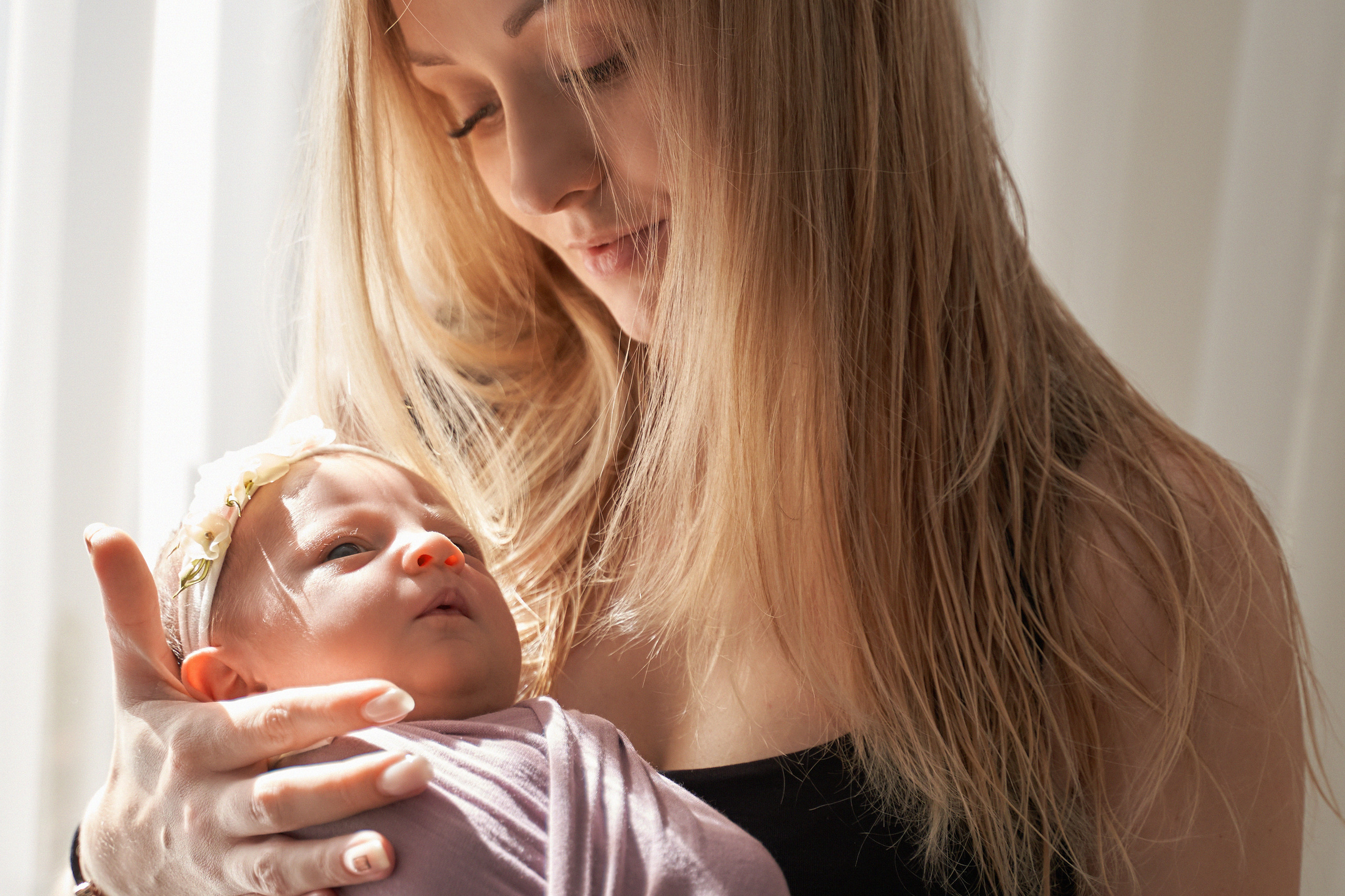 мама с новорожденной дочкой стоят у окна