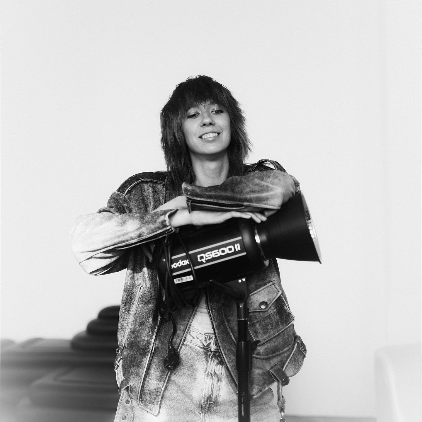 Портрет стильной девушки фотографа с рефлектором на стойке.