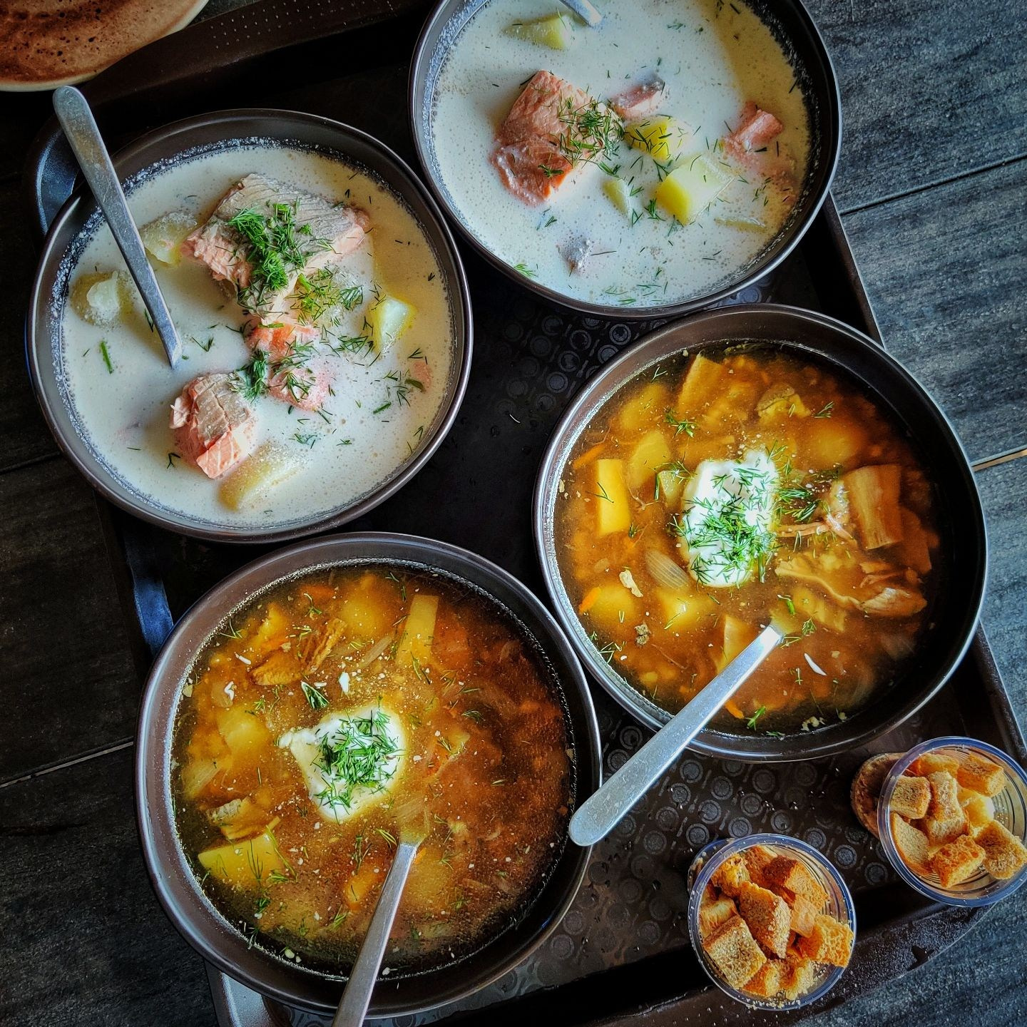 В тарелках на столе овощной суп и сливочная уха с сухариками