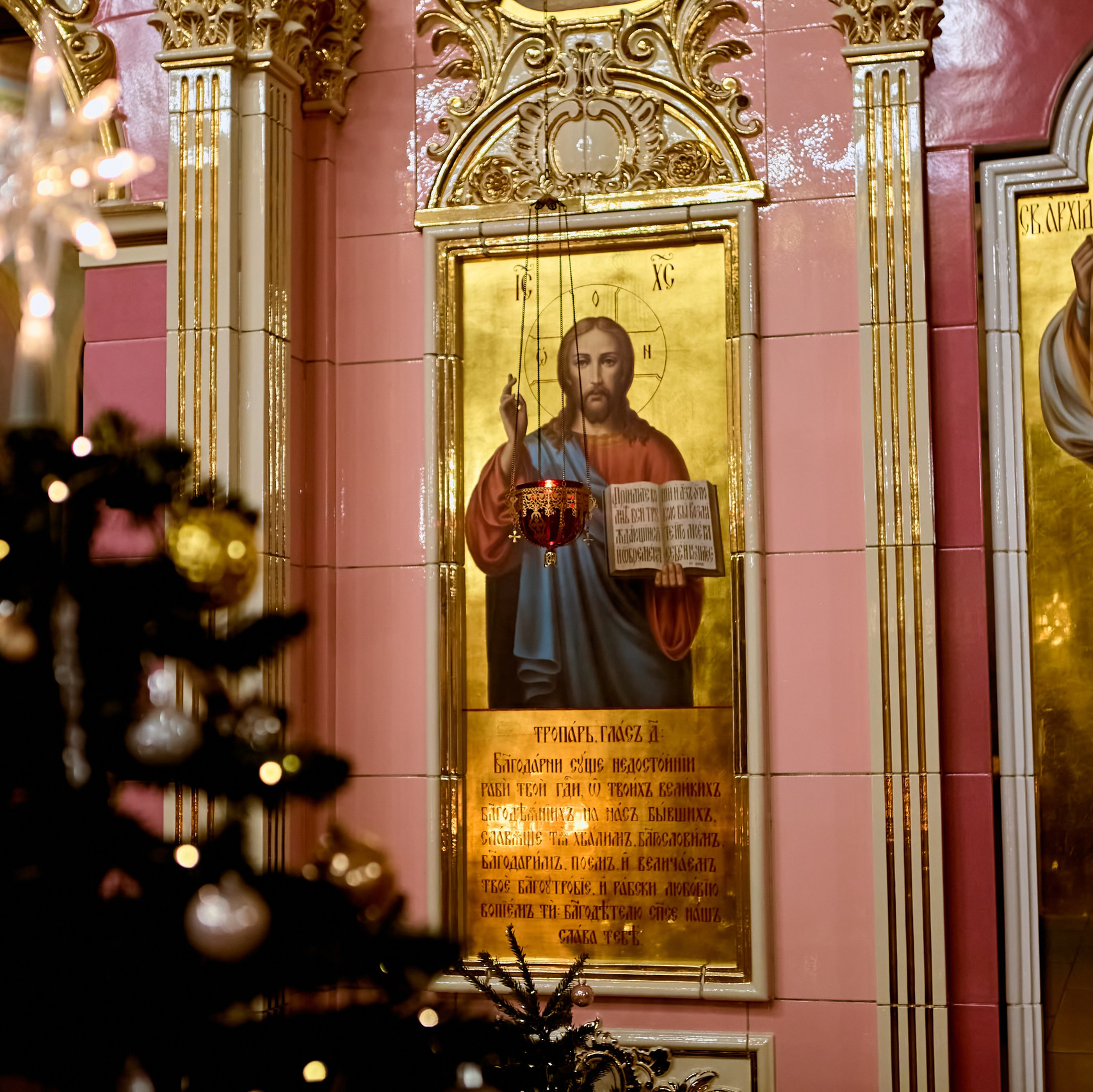 Икона Иисуса Христа в иконостасе на фоне новогодней елки