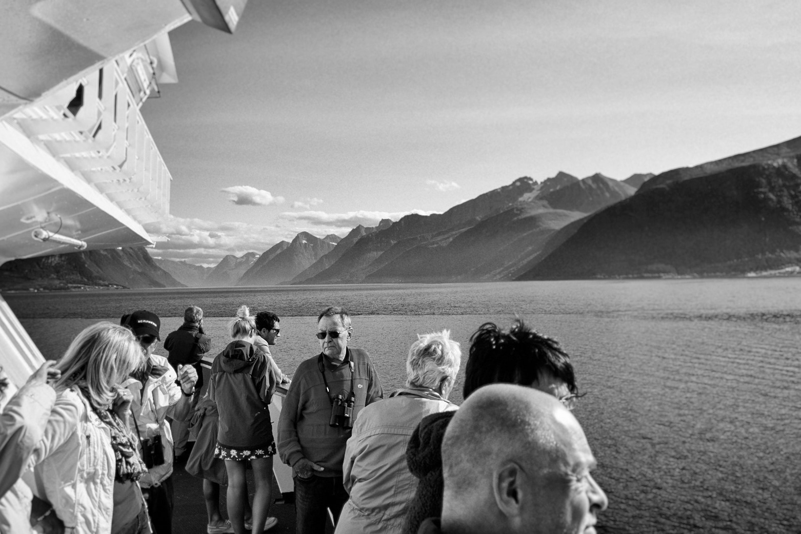 Черно-белое фото туристов на палубе корабля созерцающих фьорд с горами, пейзаж Норвегии, travel photography, документальная съемка