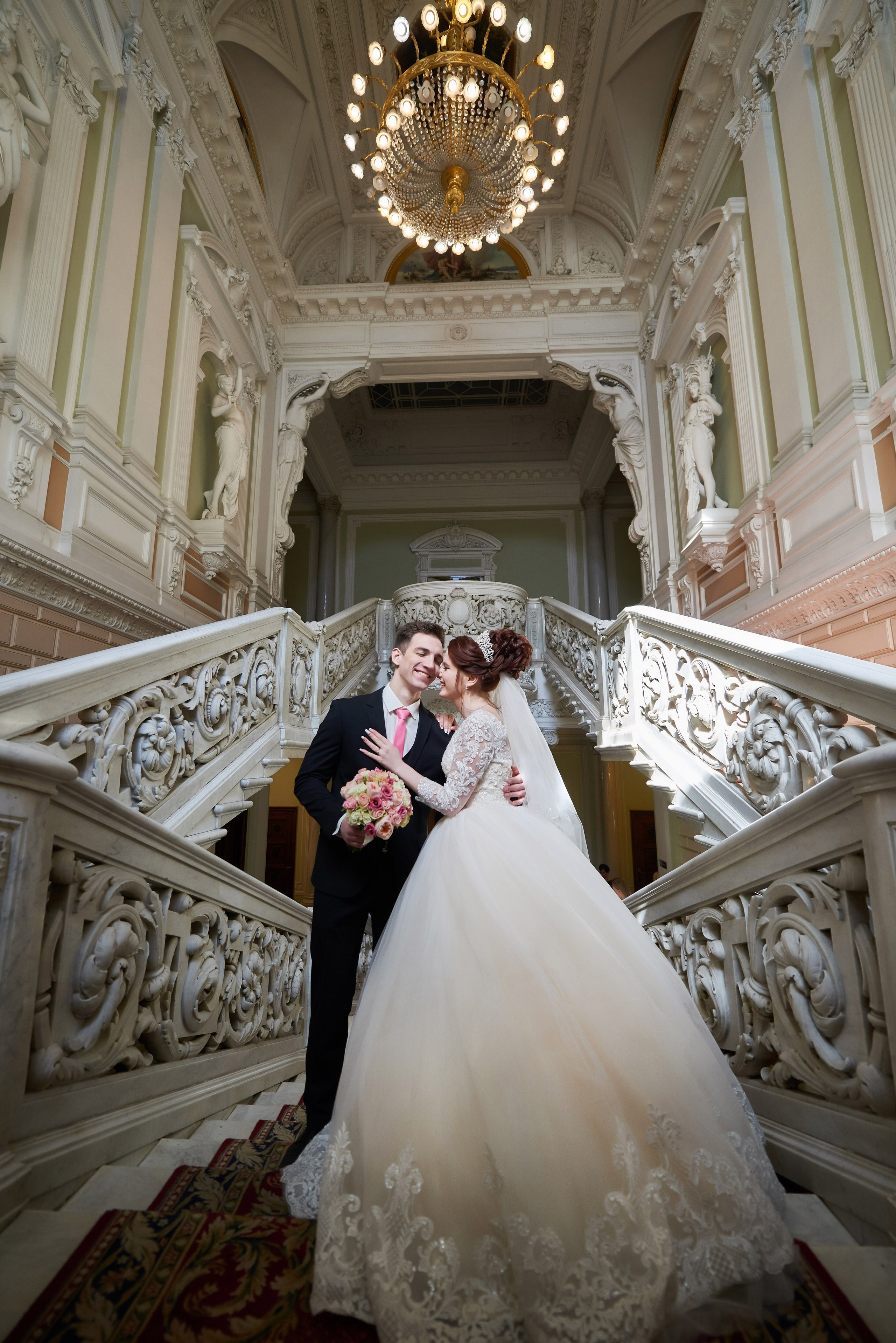 Двое молодожёнов во Дворце на Английской набережной улыбаясь обнимают друг друга